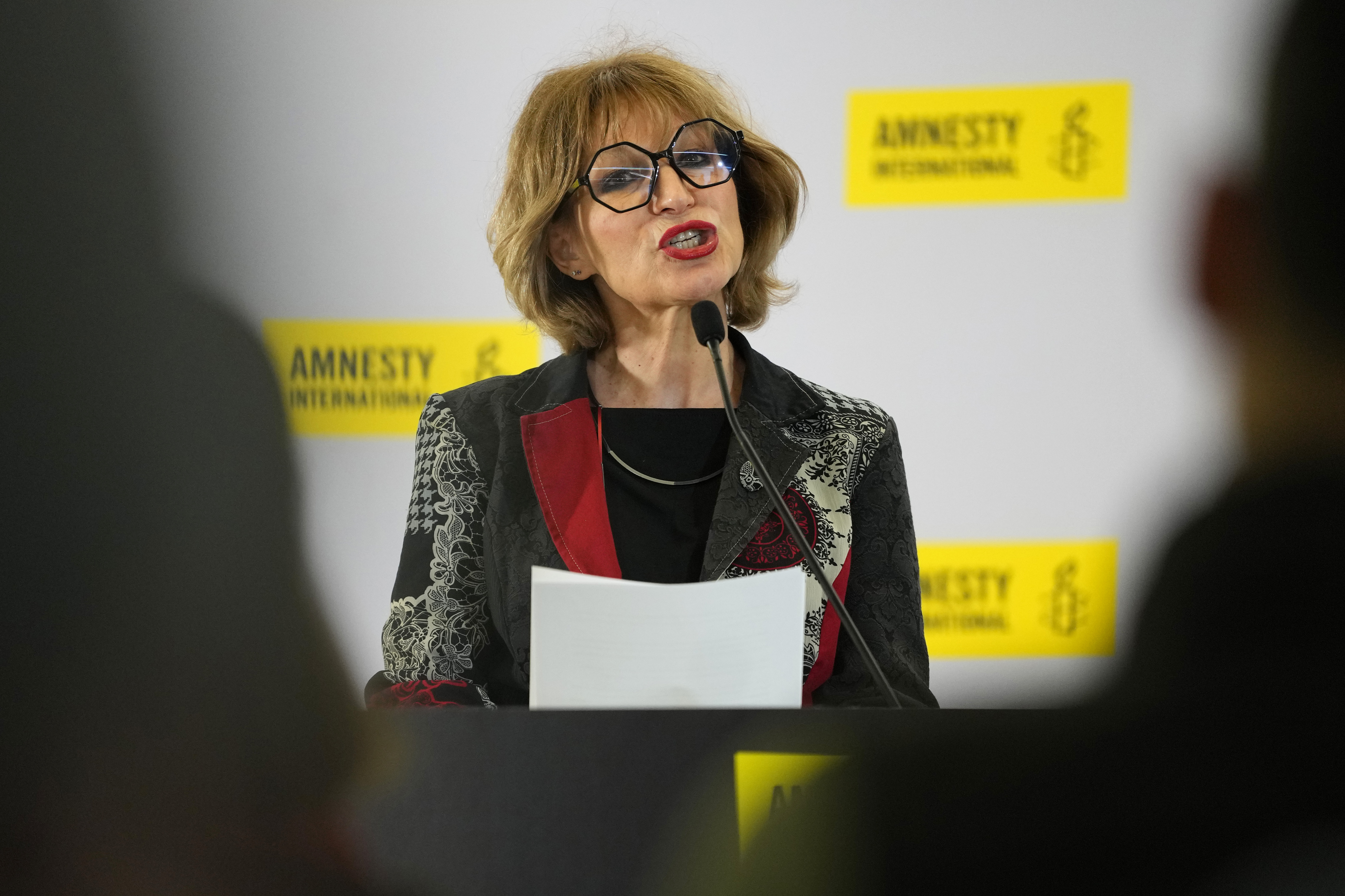 Agnes Callamard, Secretary General of Amnesty International. Callamard is speaking at a press conference. She has blonde hair and is wearing large black glasses.