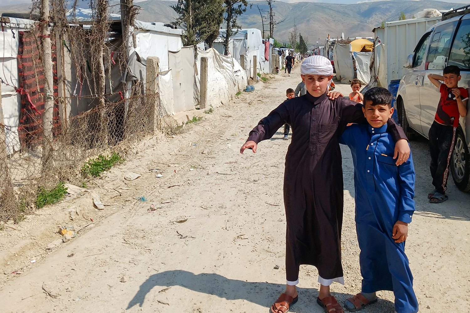 Two boys pose for a photo on a dusty street