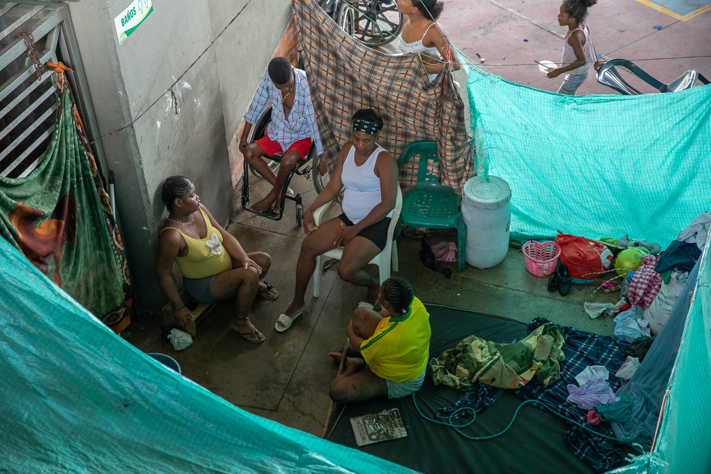 Residents of San Isidro sit between tarps and hanging sheets to get privacy in the coliseum.