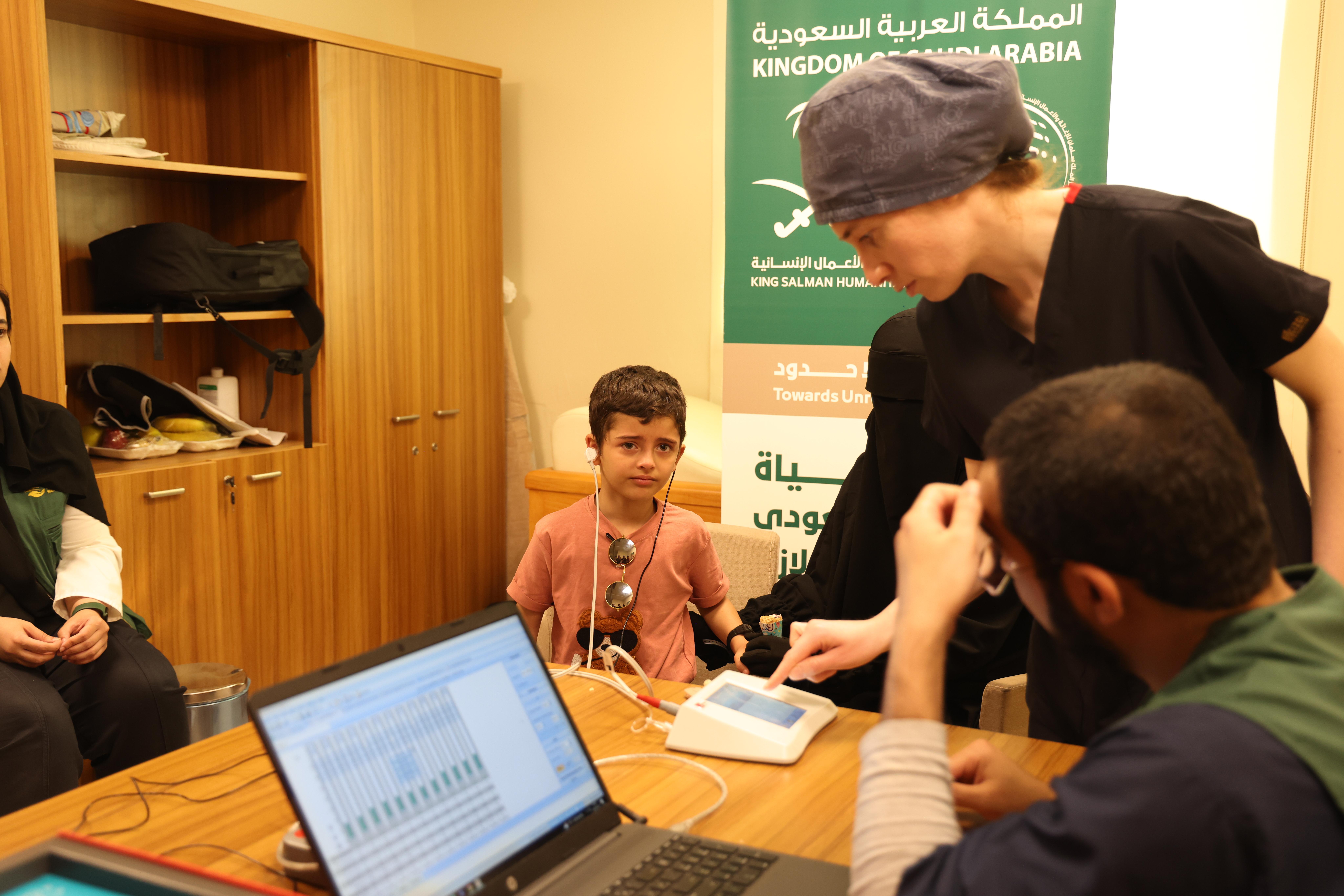 Aslan in hearing test room as technicians programme his device