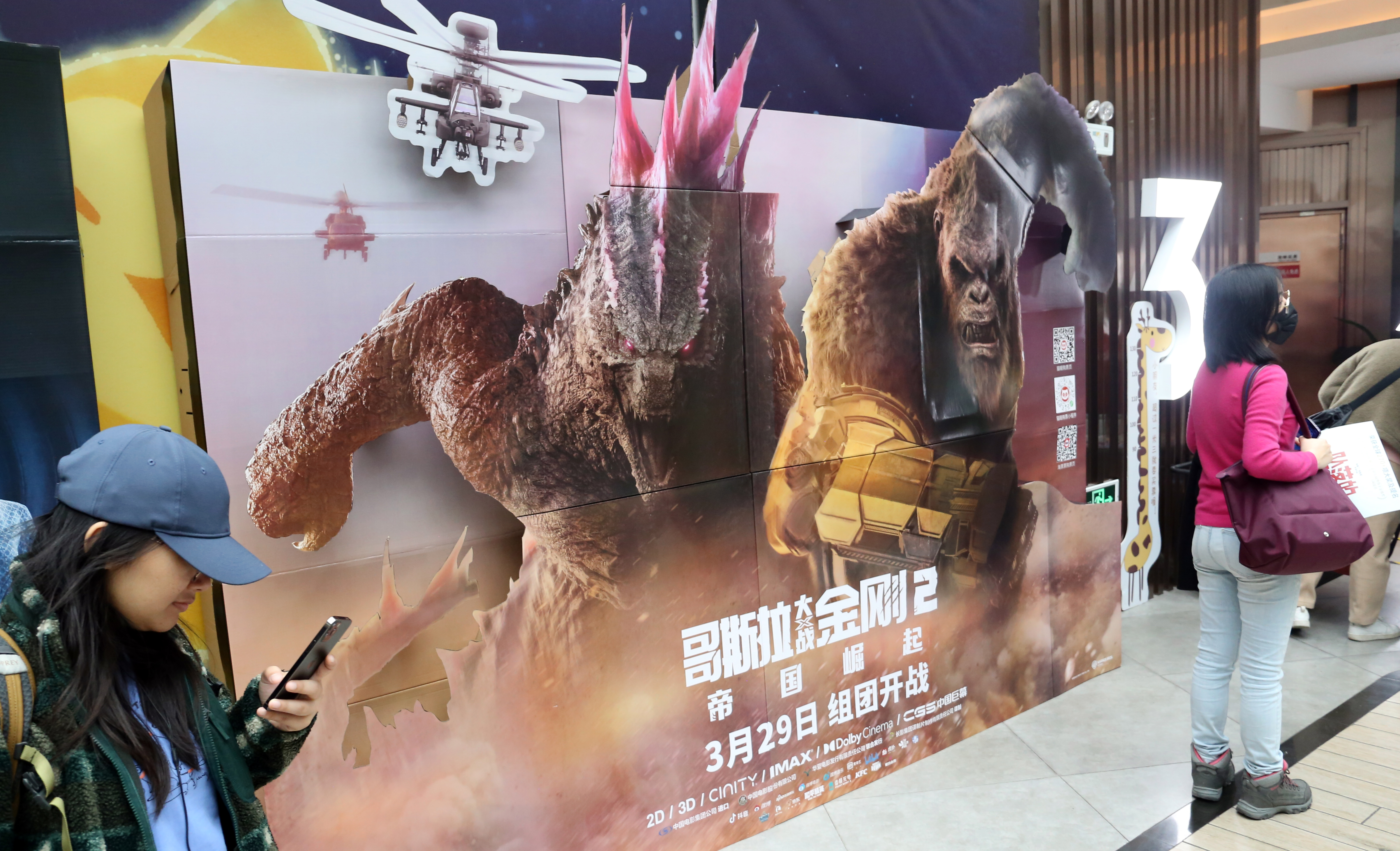 Fans pass a promotional poster for the Hollywood film Godzilla x Kong: The New Empire at a cinema in Shanghai, China, on March 23, 2024 [CFOTO/Future Publishing via Getty Images]