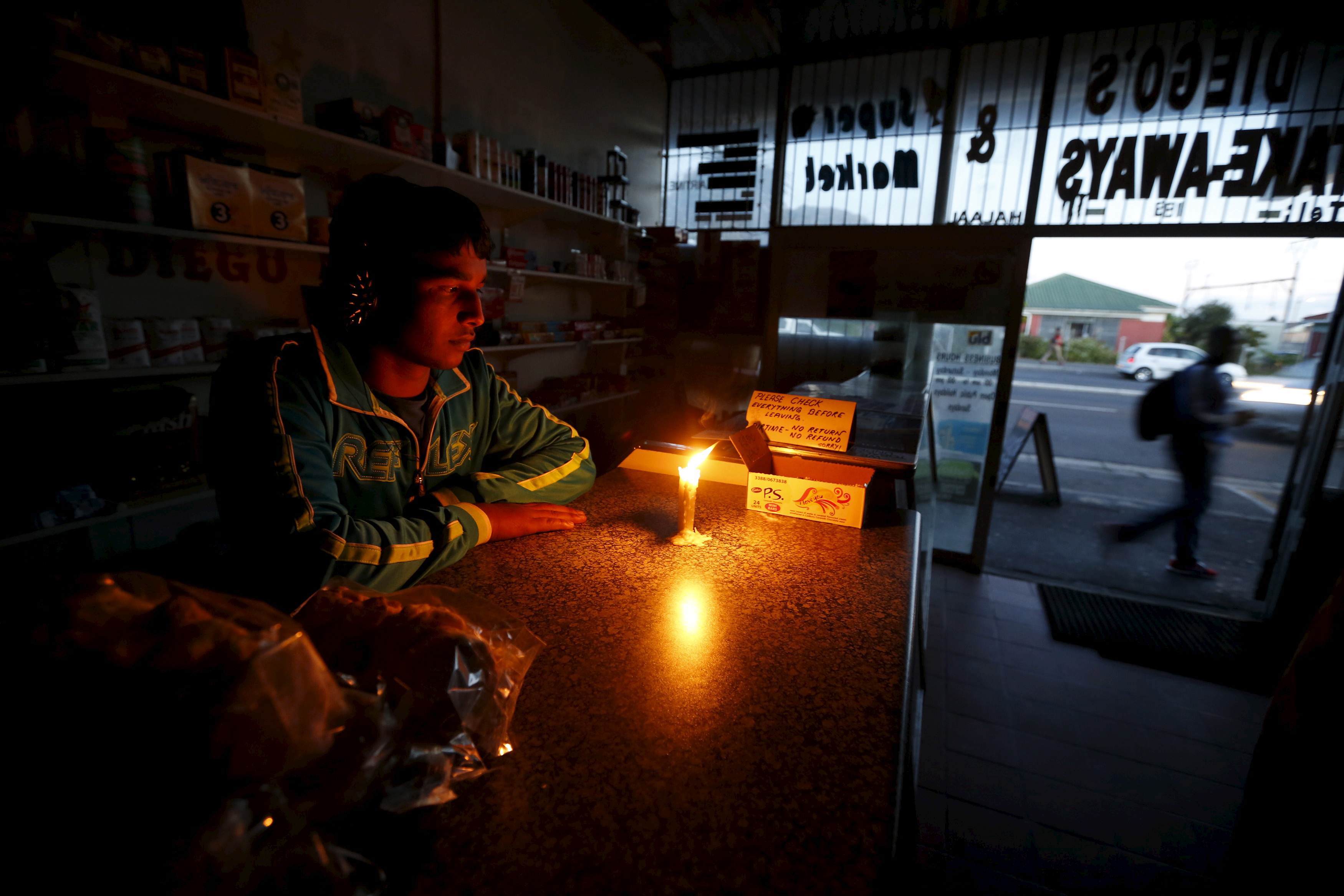 A shopkeeper in South Africa works by candle-light during a power blackout