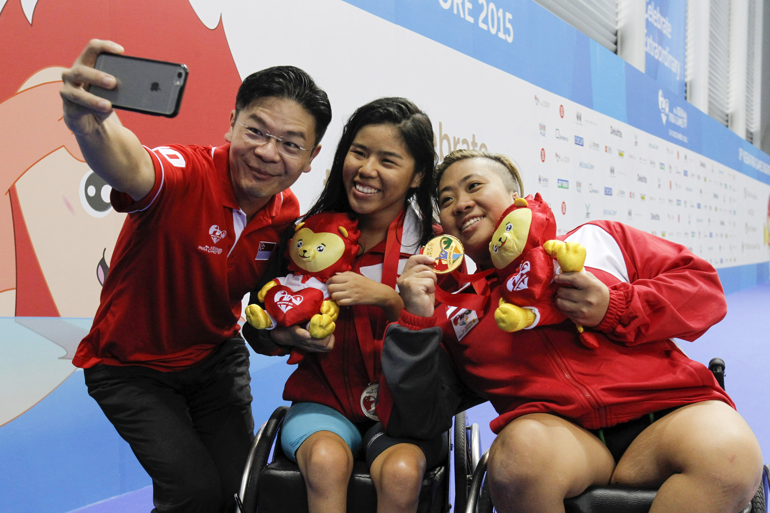 Lawrence Wong taking a selfie with two members of Singpore's team at the ASEAN Para Games in 2015. They all look happy and relaxed.