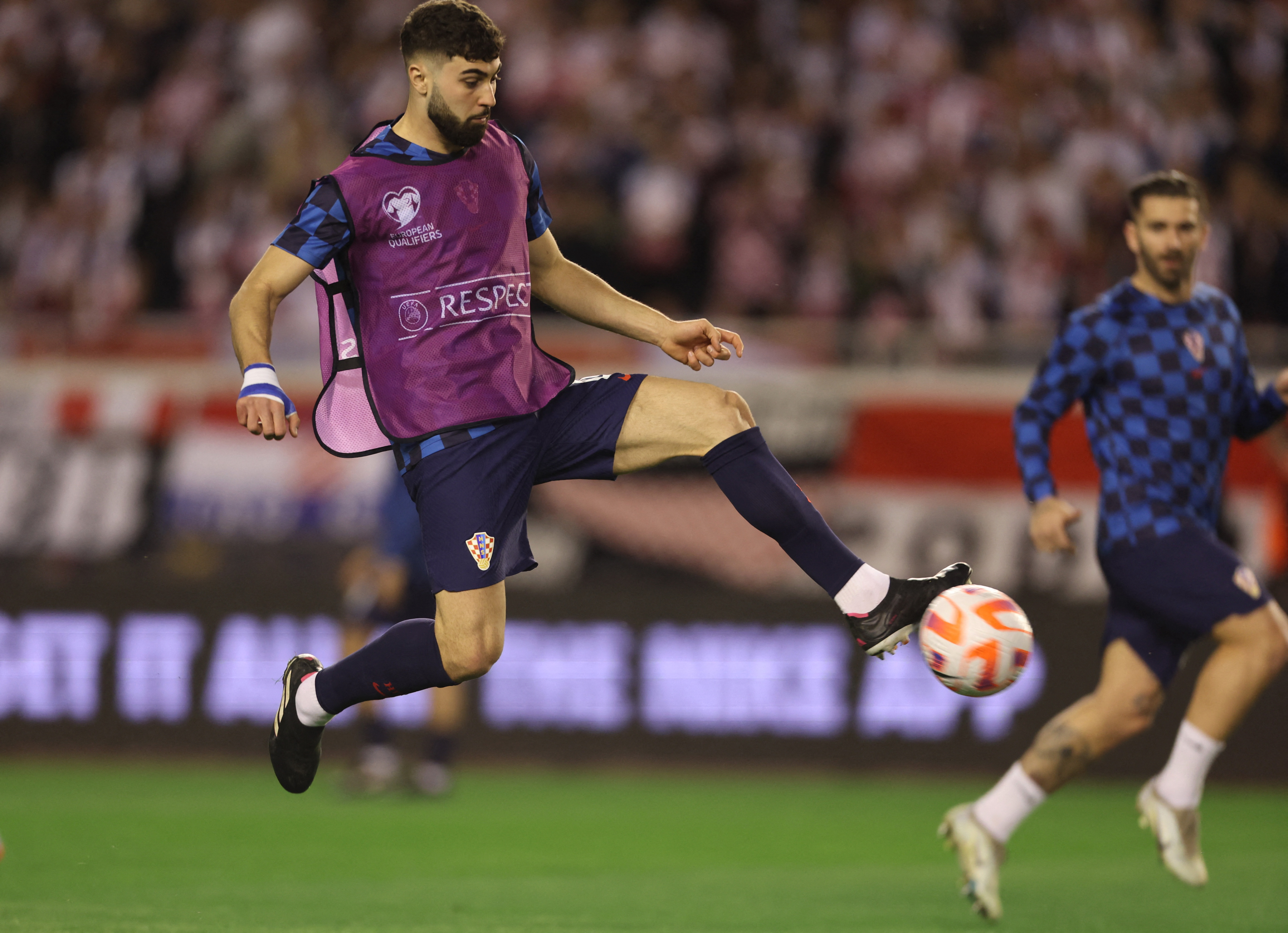 Football player catches ball with his foot.