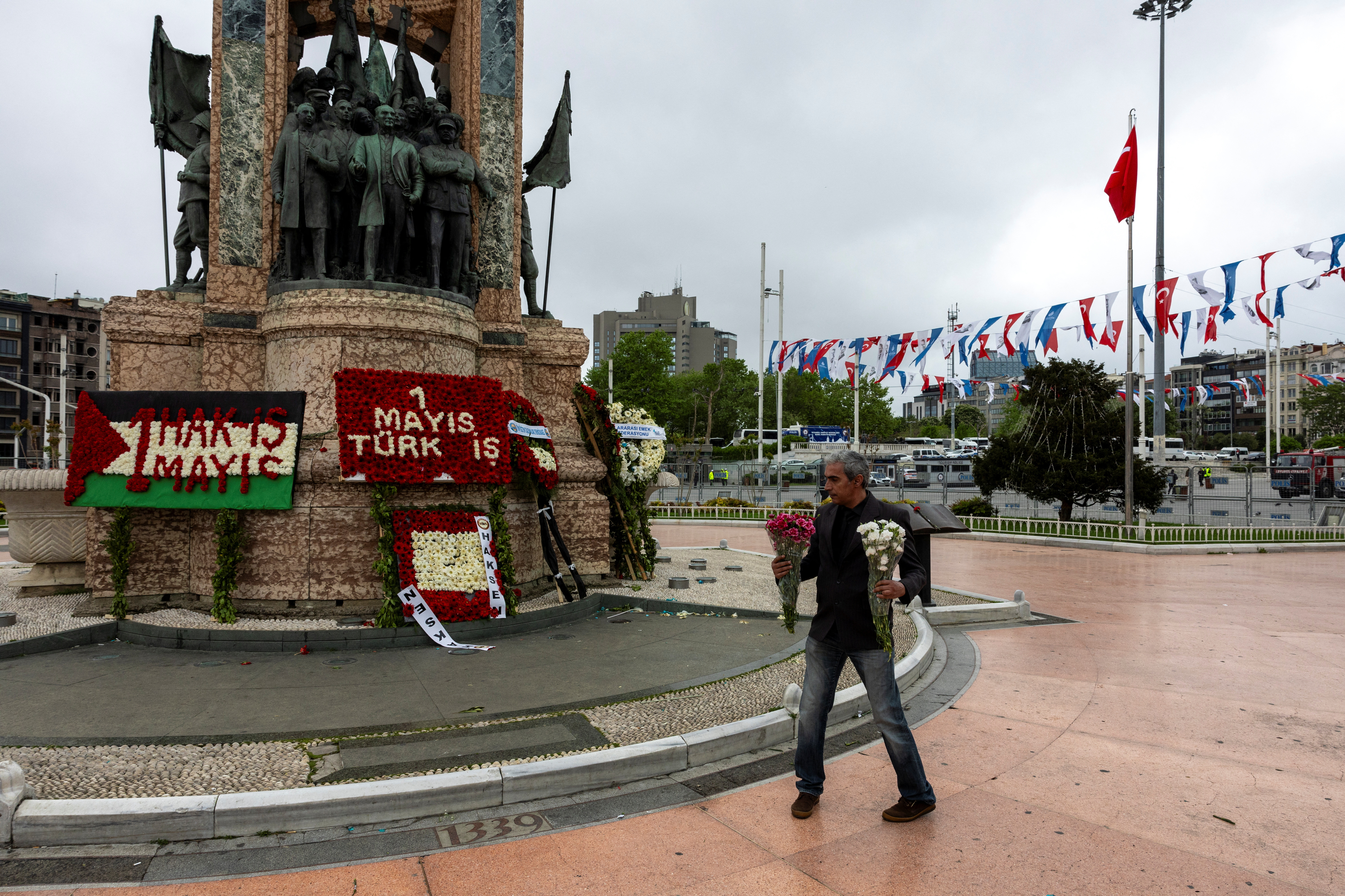 A labor union member holds flowers in front of the Victory Monument which is banned and closed for those who want to celebrate May Day at Taksim Square in Istanbul, Turkey May 1, 2024. REUTERS/Umit Bektas