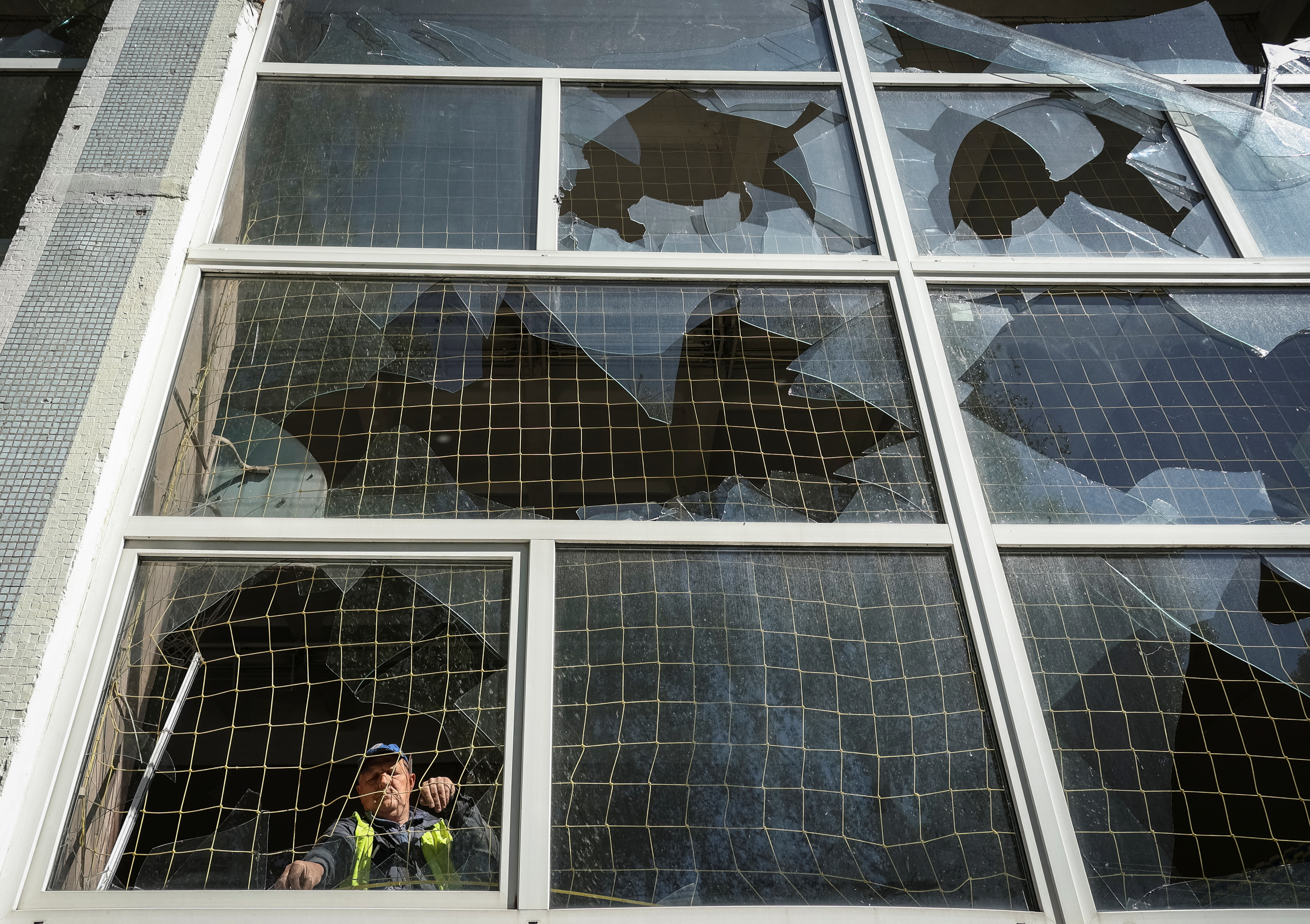 A worker removes shards of glass from a broken window of a school gym damaged by a Russian missile strike, amid Russia's attack on Ukraine, in Kharkiv, Ukraine May 8, 2024. REUTERS/Sofiia Gatilova