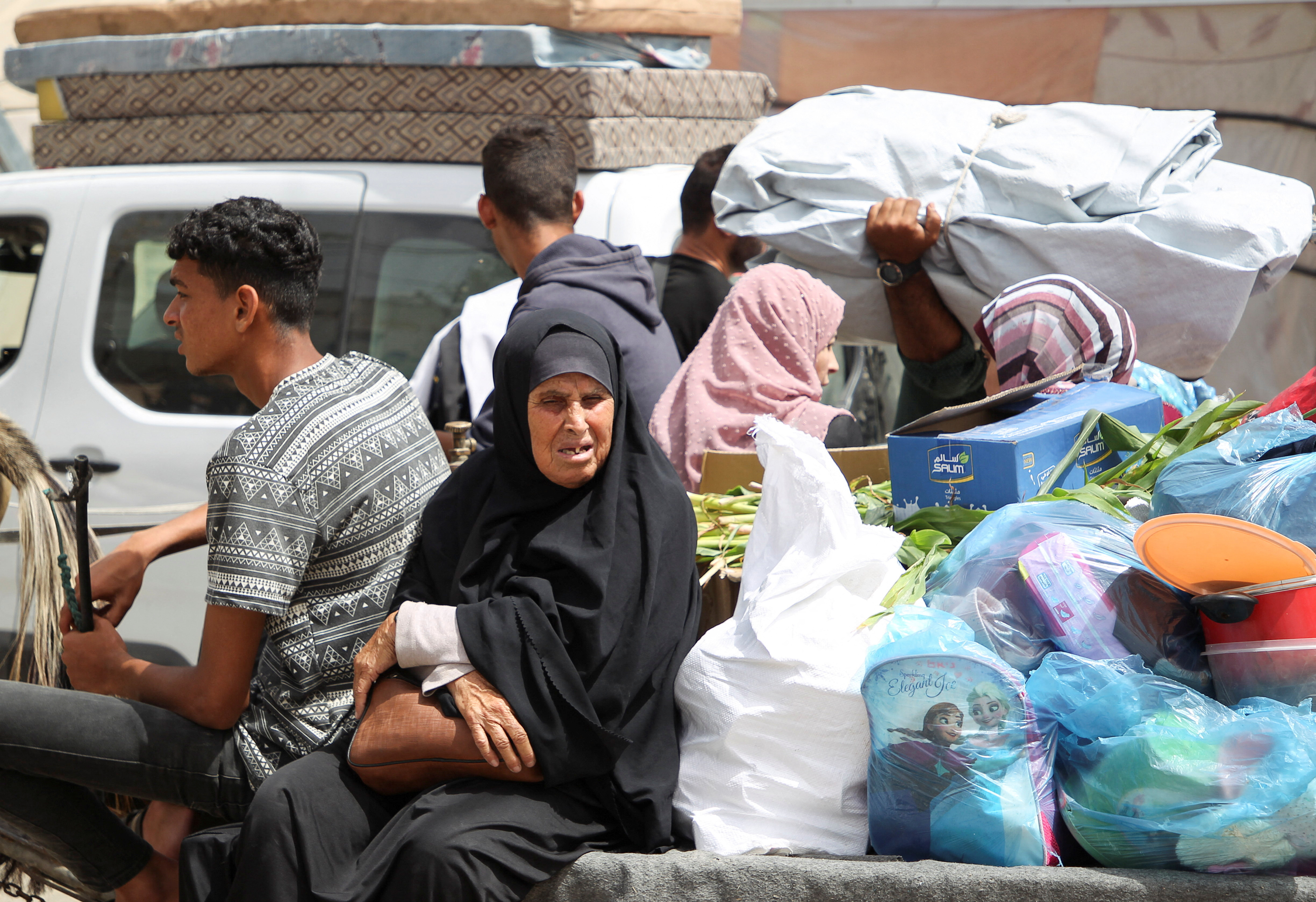 A woman sits next to belongings, as Palestinians prepare to evacuate