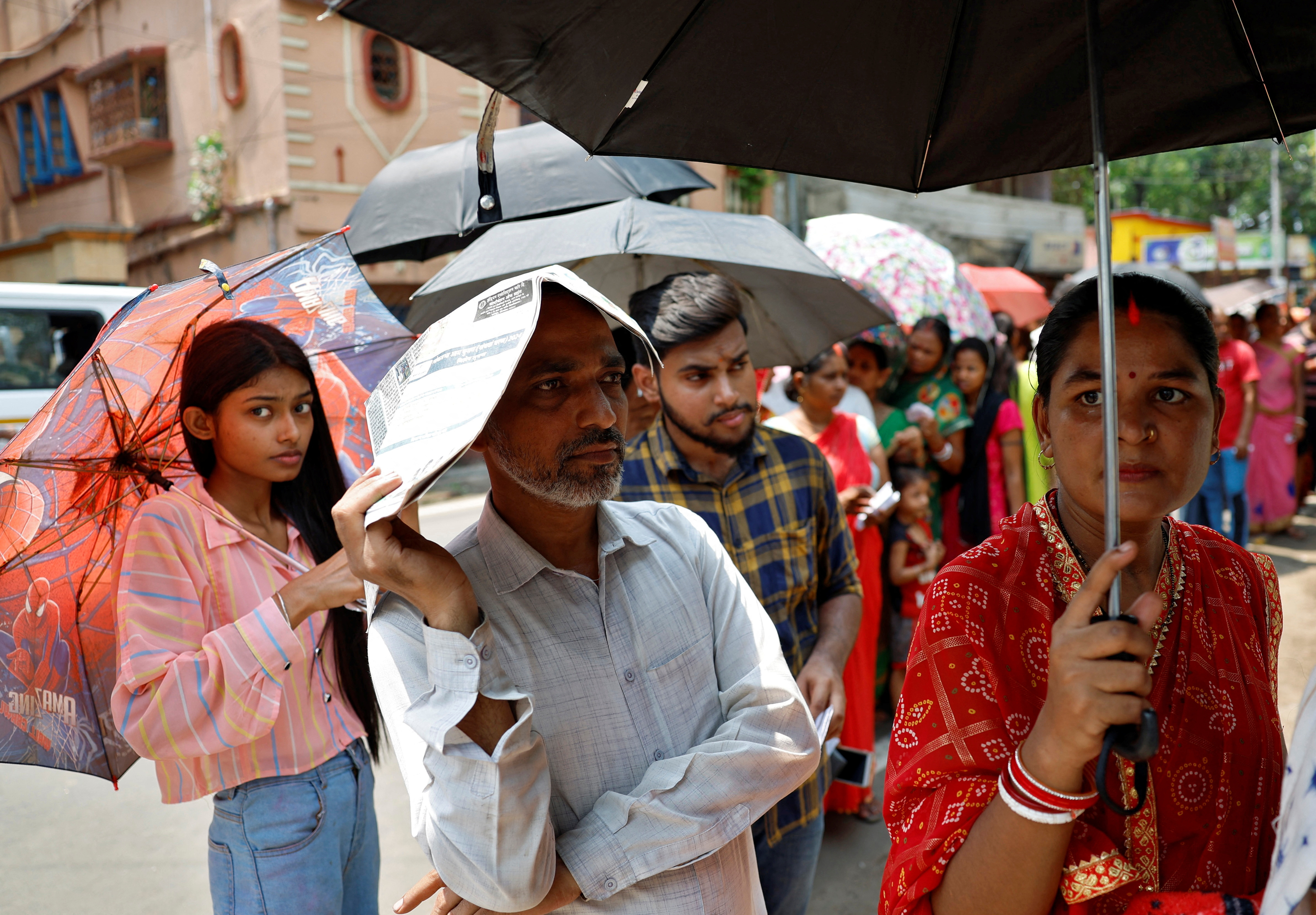 A man uses a newspaper as others use umbrellas to protect themselves from the heat as they wait to vote outside a polling station during the fifth phase of India’s general election in Howrah district of the eastern state of West Bengal, India, May 20, 2024. REUTERS/Sahiba Chawdhary