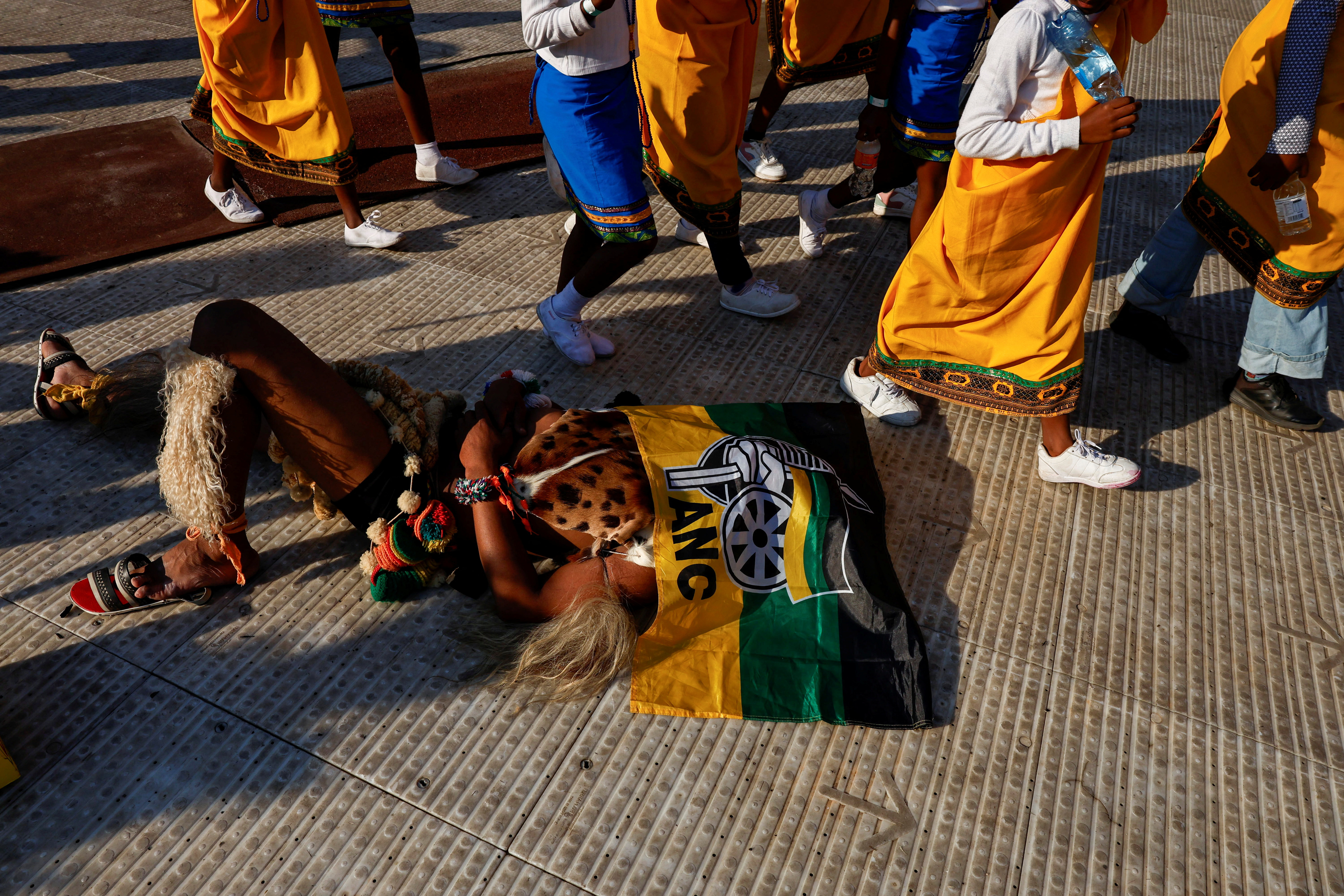 A supporter rests under the flag of the African National Congress (ANC) during the party's final rally ahead of the upcoming elections at the FNB Stadium in Johannesburg, South Africa May 25, 2024 REUTERS/James Oatway