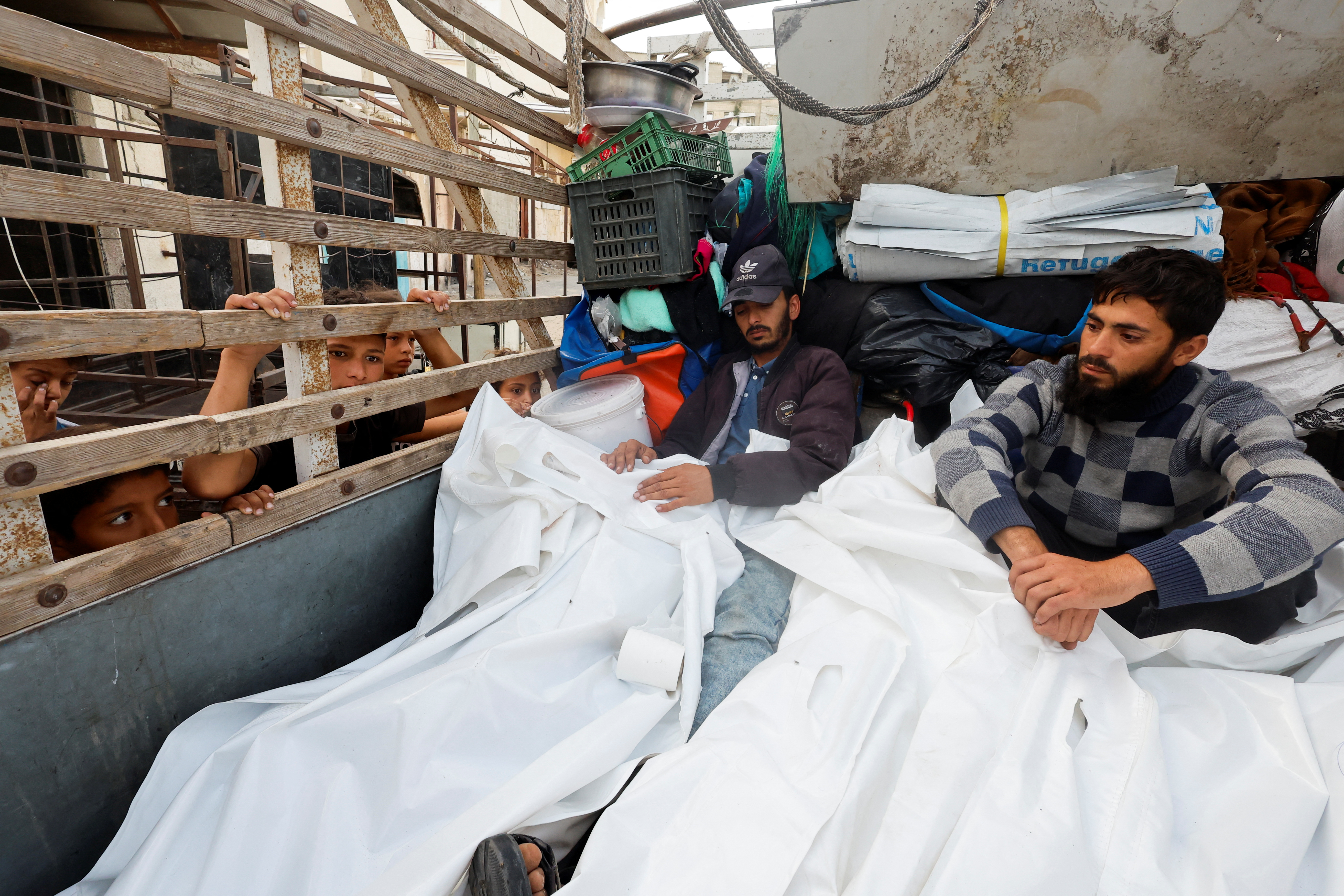 Mourners sit with the bodies of Palestinians killed in an Israeli strike on an area designated for displaced people