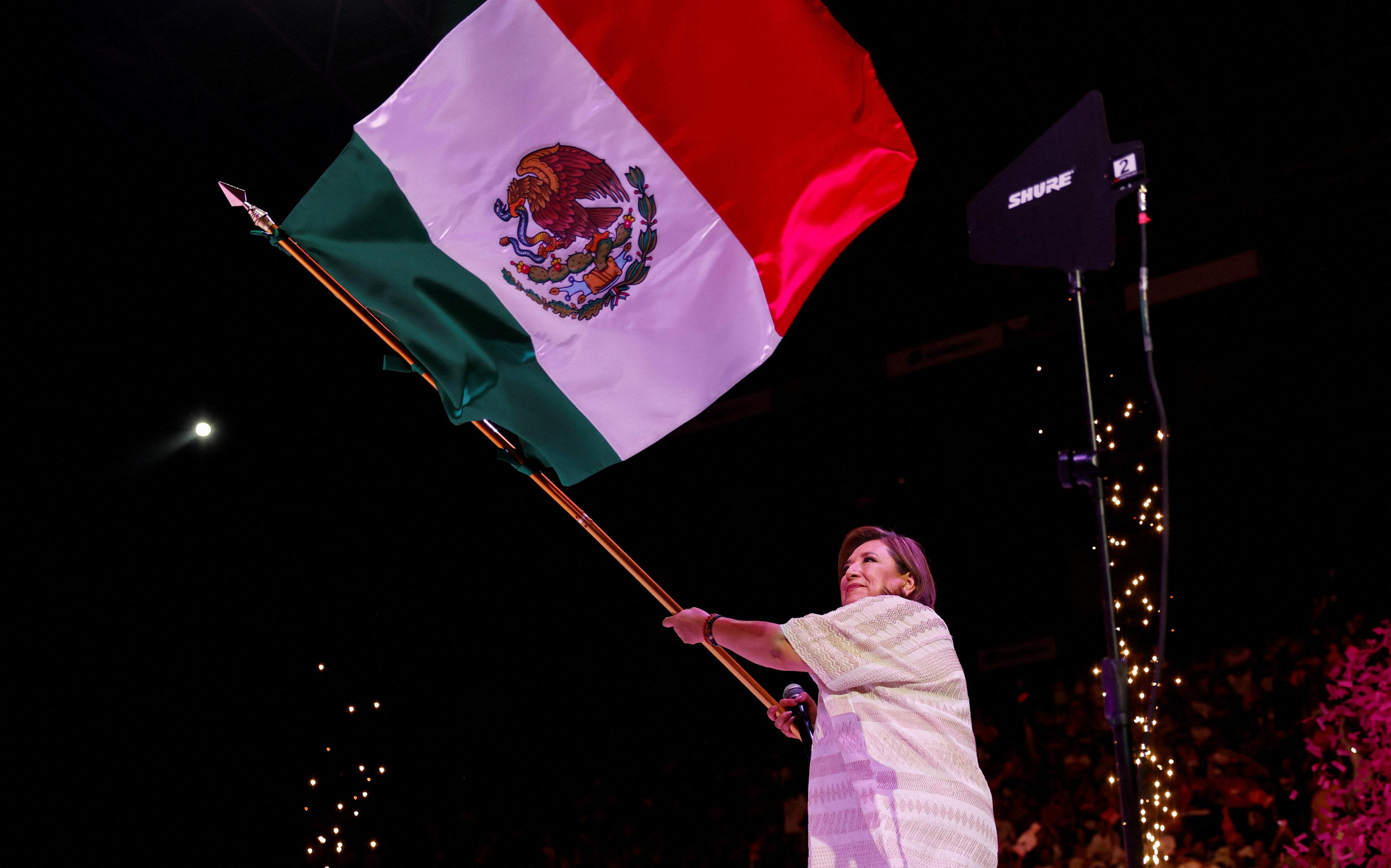 Xochitl Galvez waves a Mexican flag from the stage of her final campaign rally in 2024.