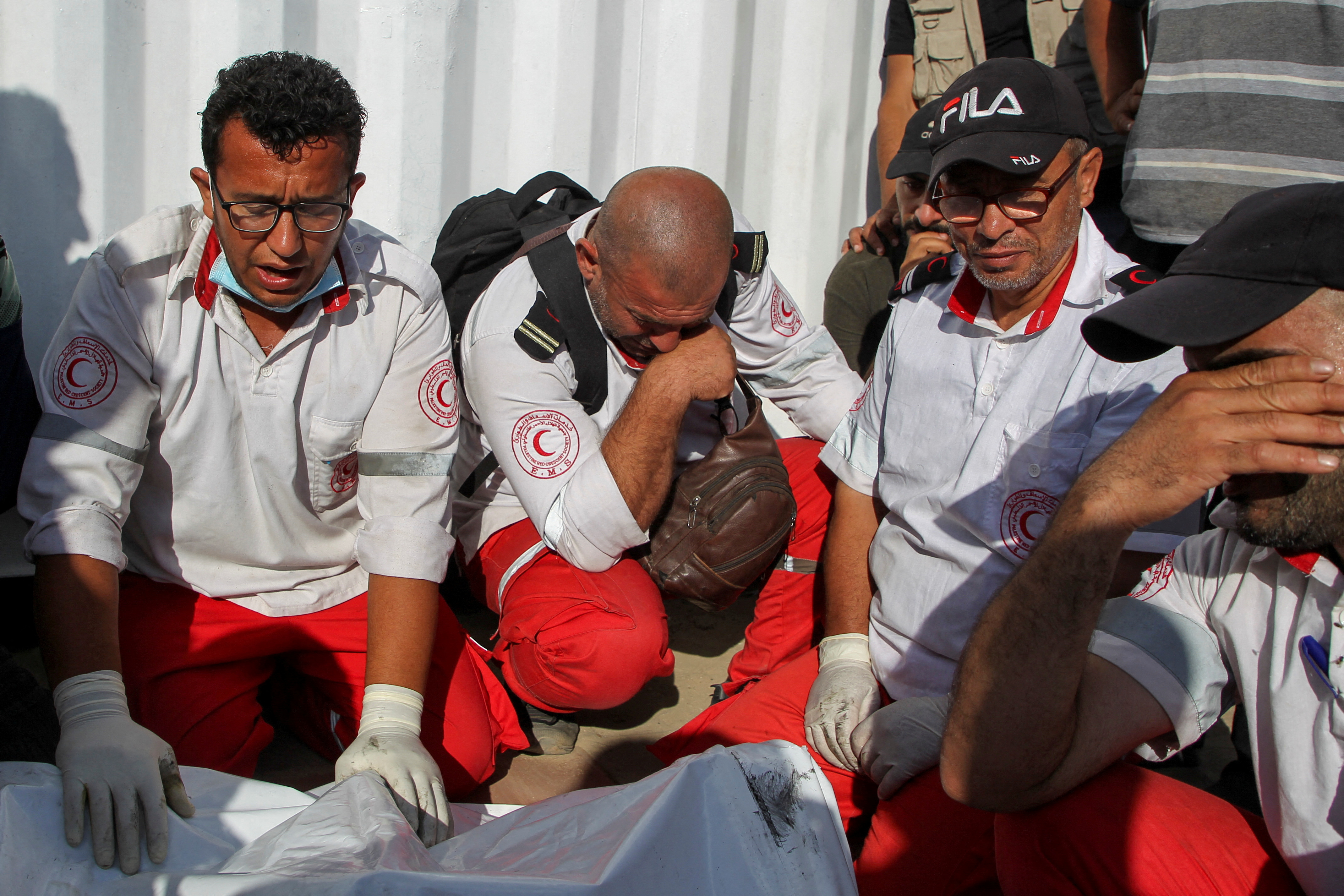Palestinian members of Palestine Red Crescent Society (PRCS) react near the bodies of their two fellow paramedics.
