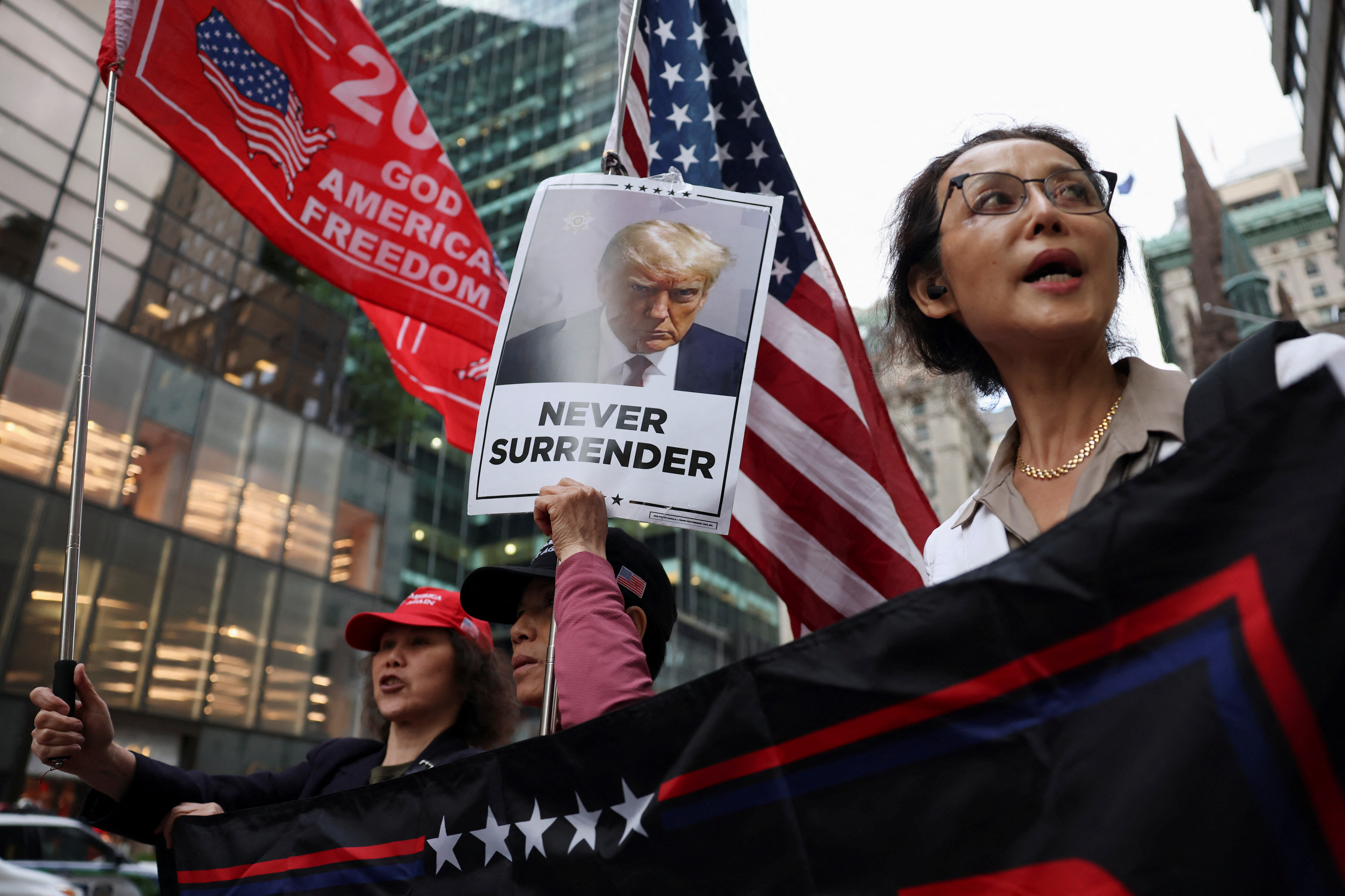 Supporters hold placards and flags following the announcement of the verdict in former U.S. President Donald Trump's criminal trial over charges that he falsified business records to conceal money paid to silence porn star Stormy Daniels in 2016, outside Trump Tower, in New York City, U.S. May 30, 2024. REUTERS/Andrew Kelly