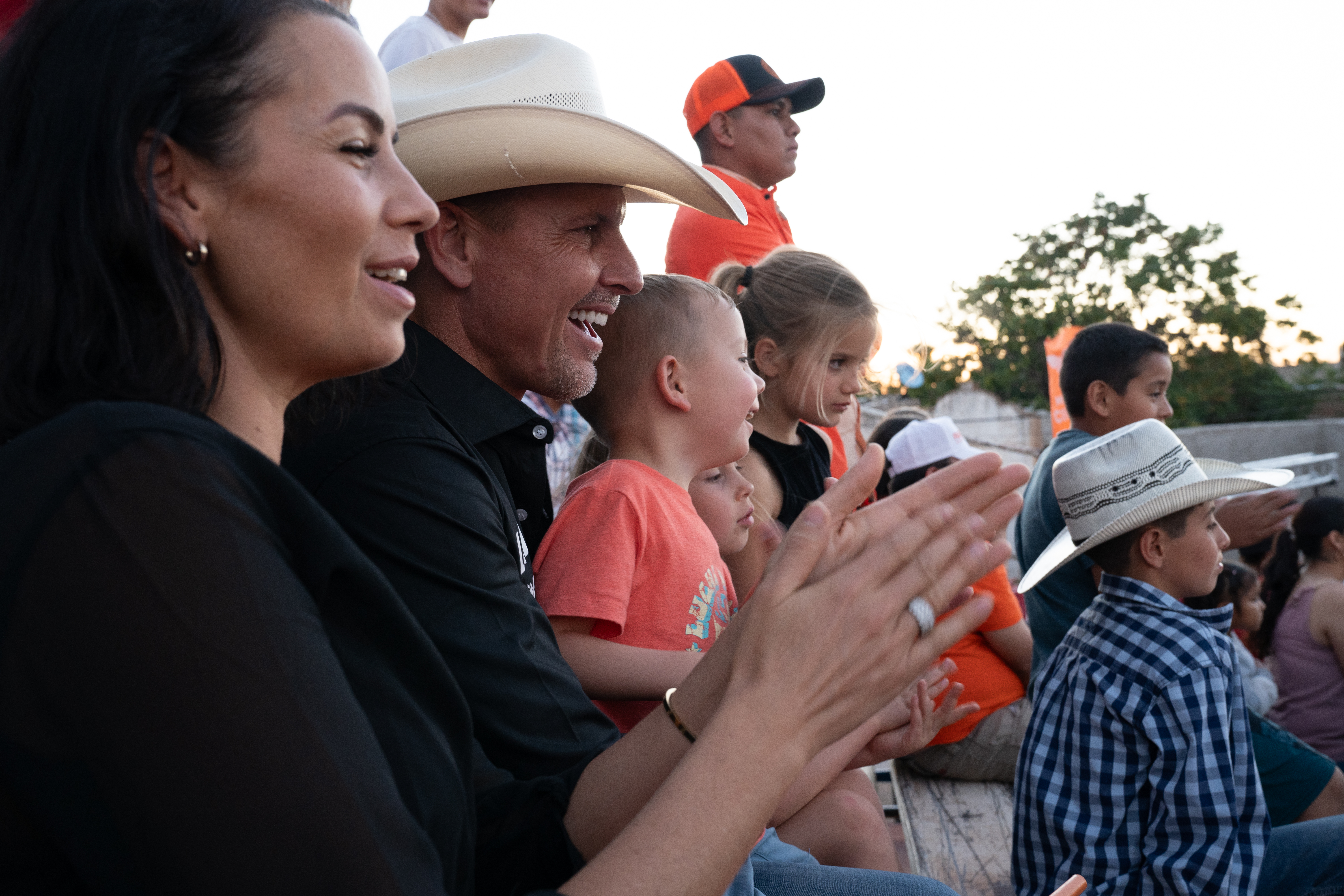 Bryan LeBaron and his family clap as they watch a rodeo.