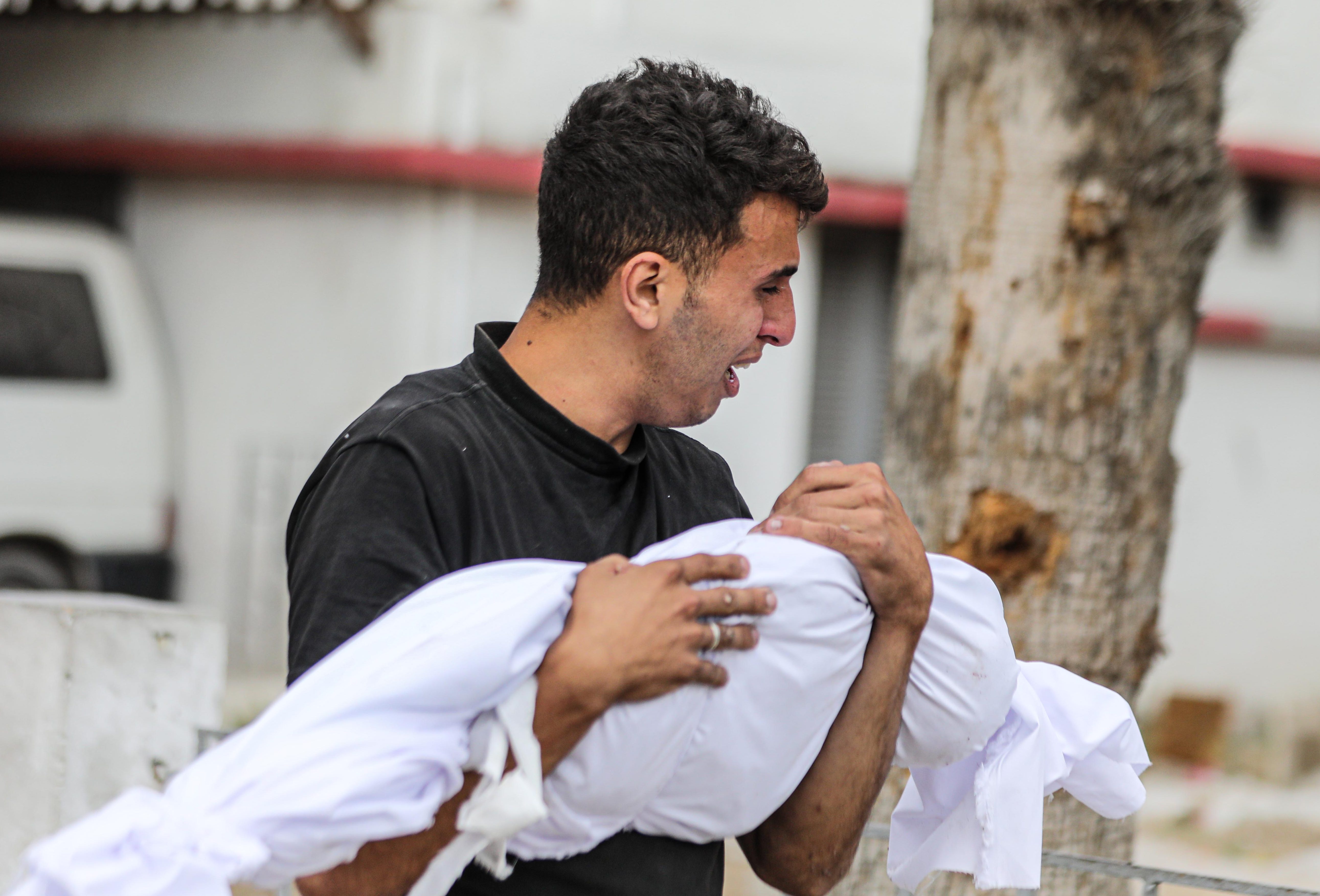 A Palestinian holds the shrouded body of a relative Israel killed in attacks on Gaza City, on May 16, 2024 [Dawoud Abo Alkas/Anadolu]