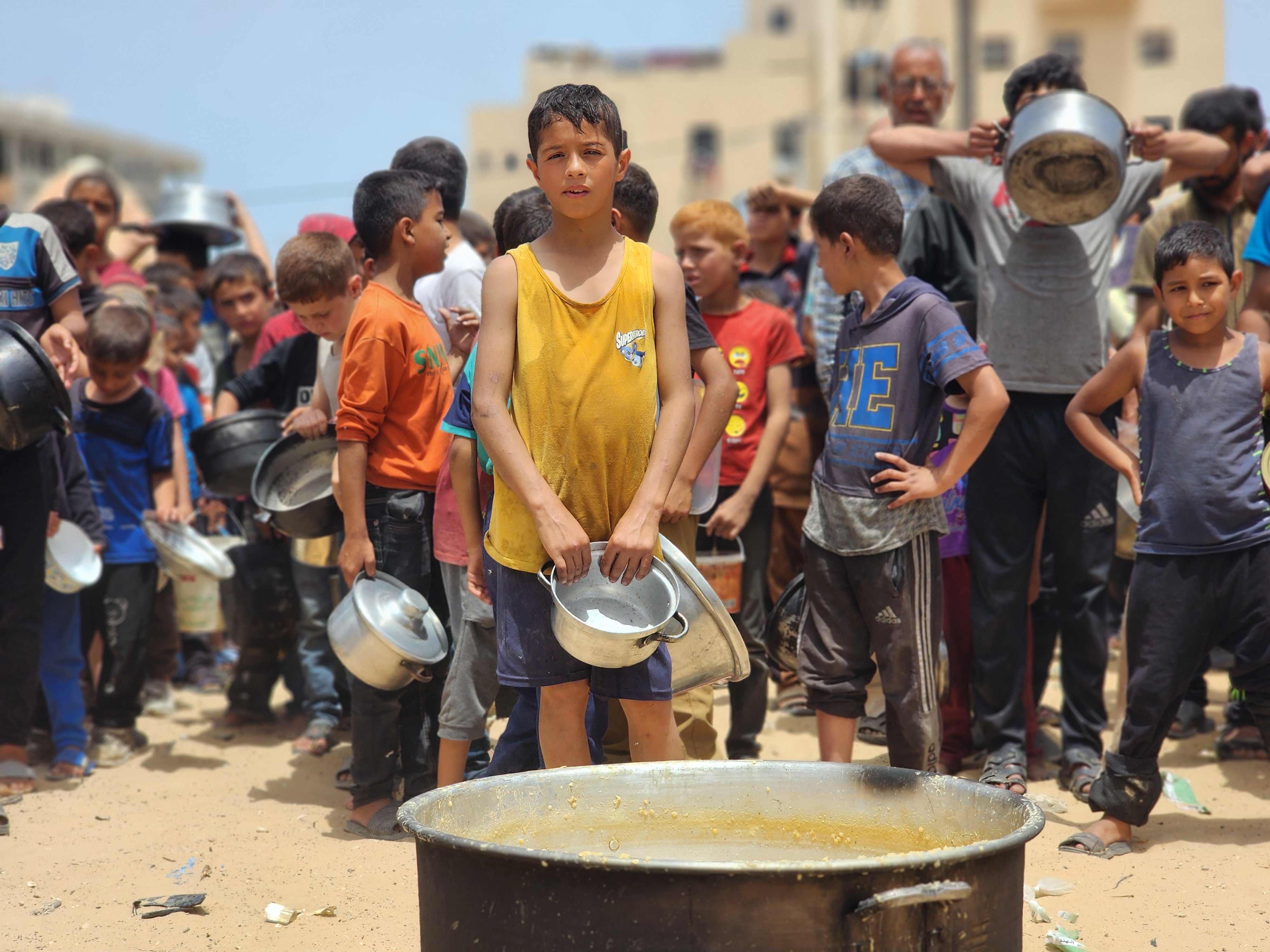 Palestinians queue with their containers for food distributed by charities at the only food distribution center that survived in Rafah city after the Israeli attacks in Rafah, Gaza on May 19
