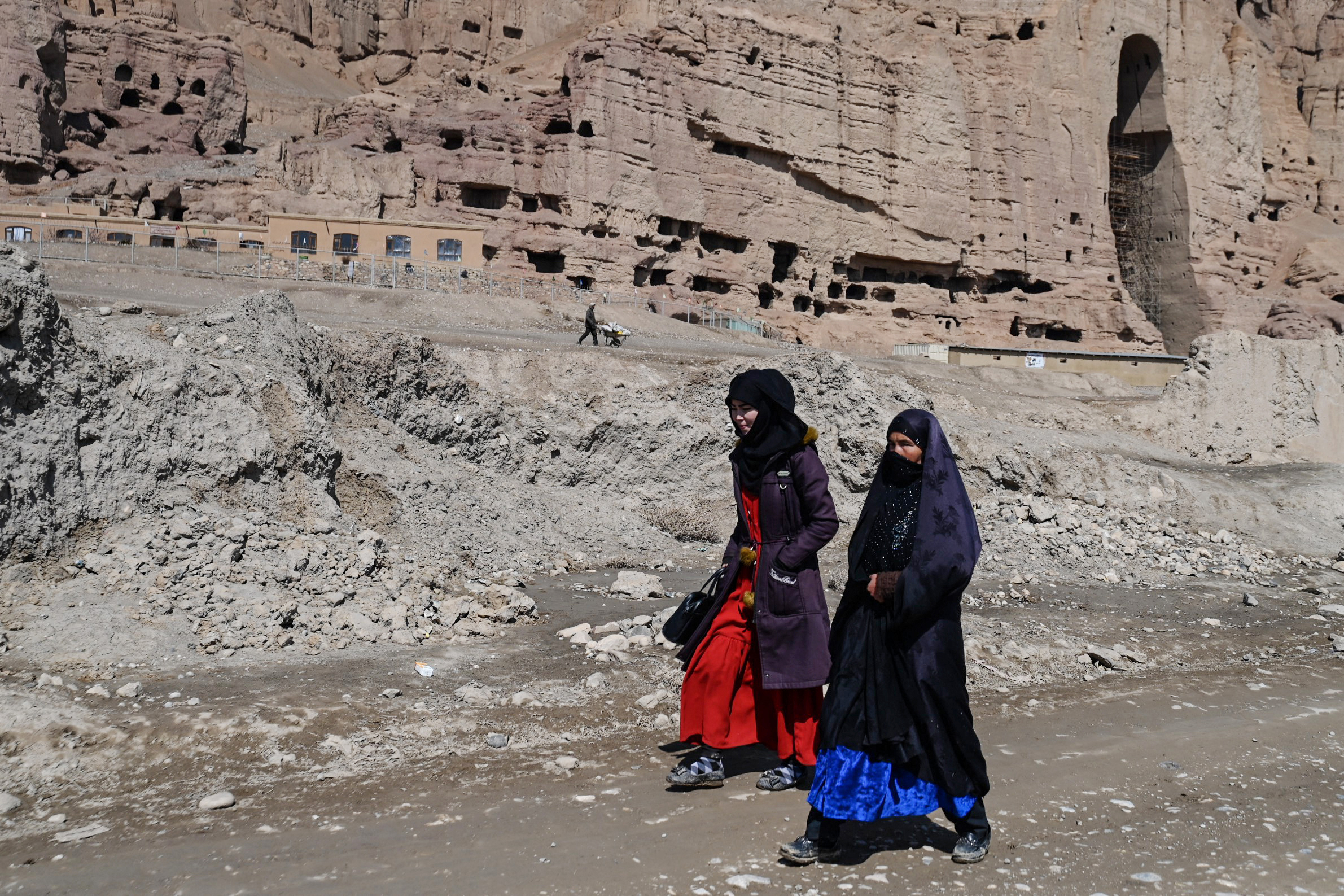TOPSHOT - Afghan Hazara women walk along a road near the site of the Buddhas of Bamiyan statues, which were destroyed by the Taliban in 2001, in Bamiyan province on March 7, 2024. (Photo by Wakil kohsar / AFP)
