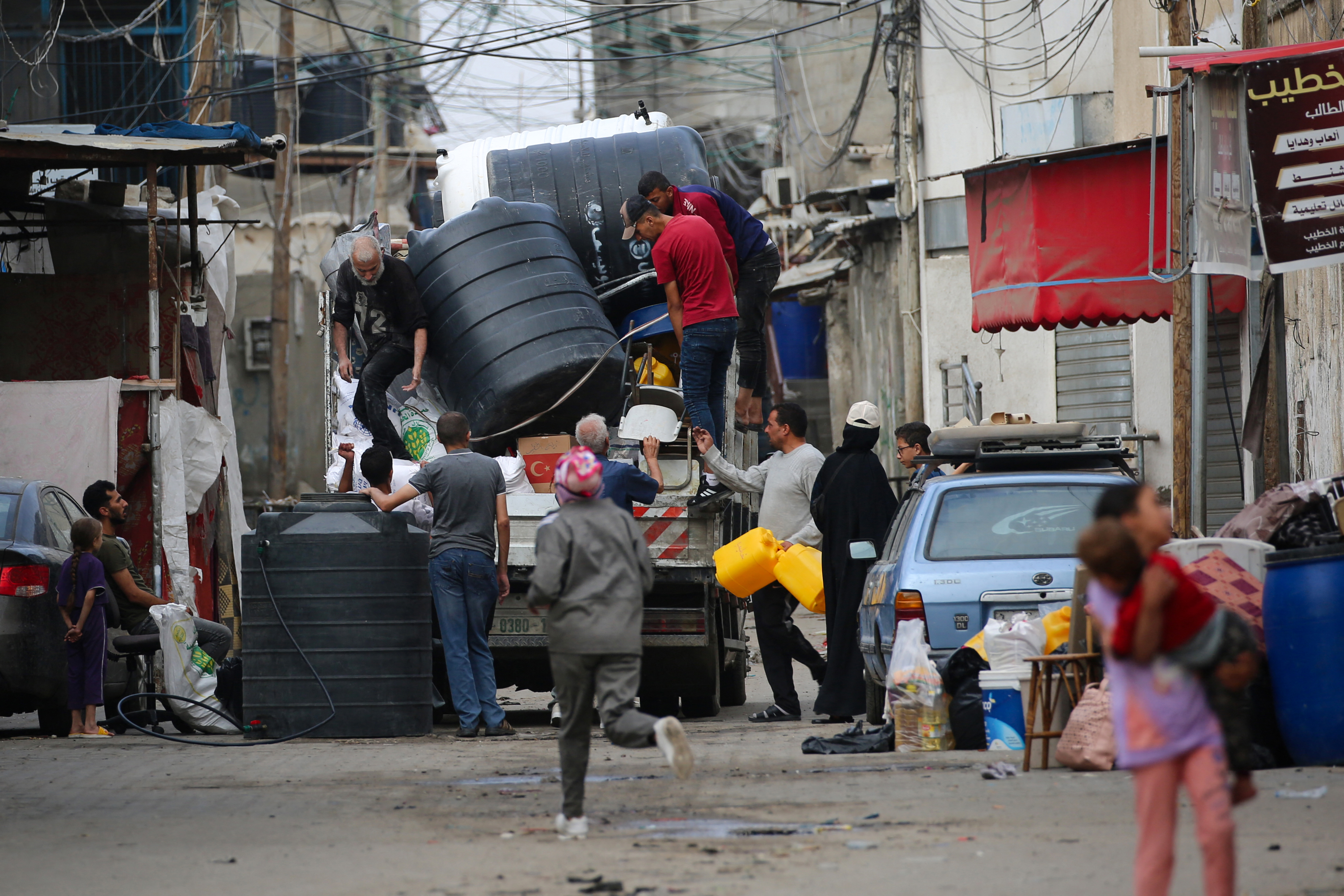 Palestinians load water containers on the back of a truck as people flee Rafah in the southern Gaza Strip to a safer location on May 11, 2023, amid the ongoing conflict between Israel and the militant group Hamas. Israeli strikes hit Gaza on May 11 after renewed US criticism over its conduct of the war and a UN warning of "epic" disaster if an outright invasion of crowded Rafah city occurs. (Photo by AFP)