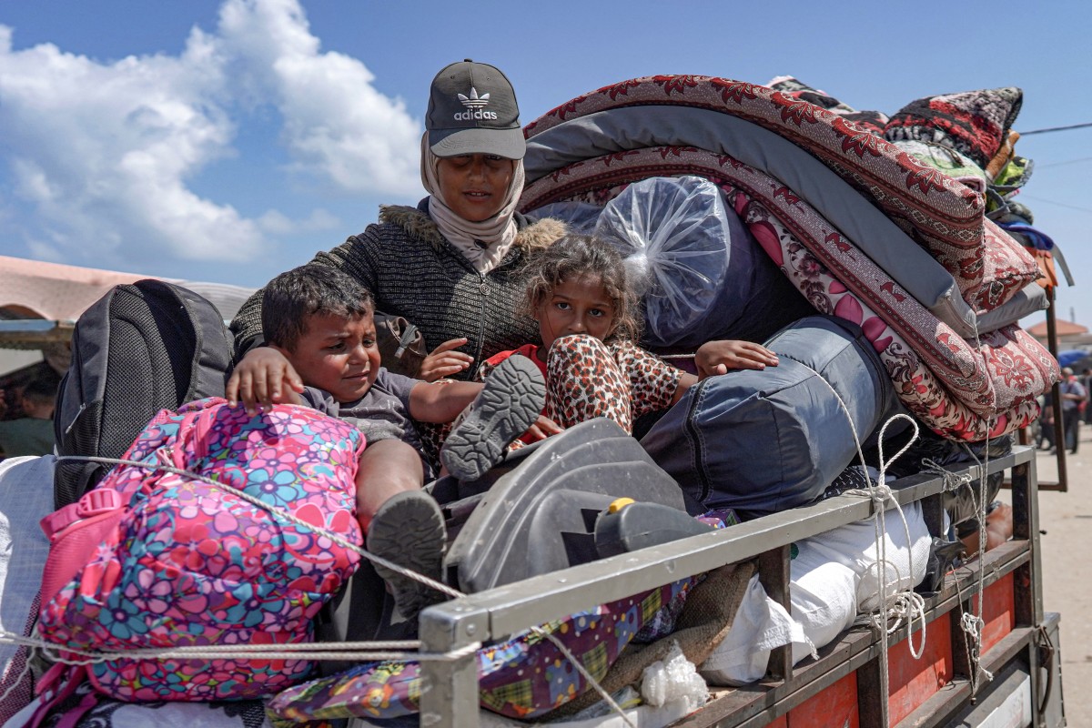 Palestinian who fled Rafah in the southern Gaza Strip ride with their belongings in the back of a truck
