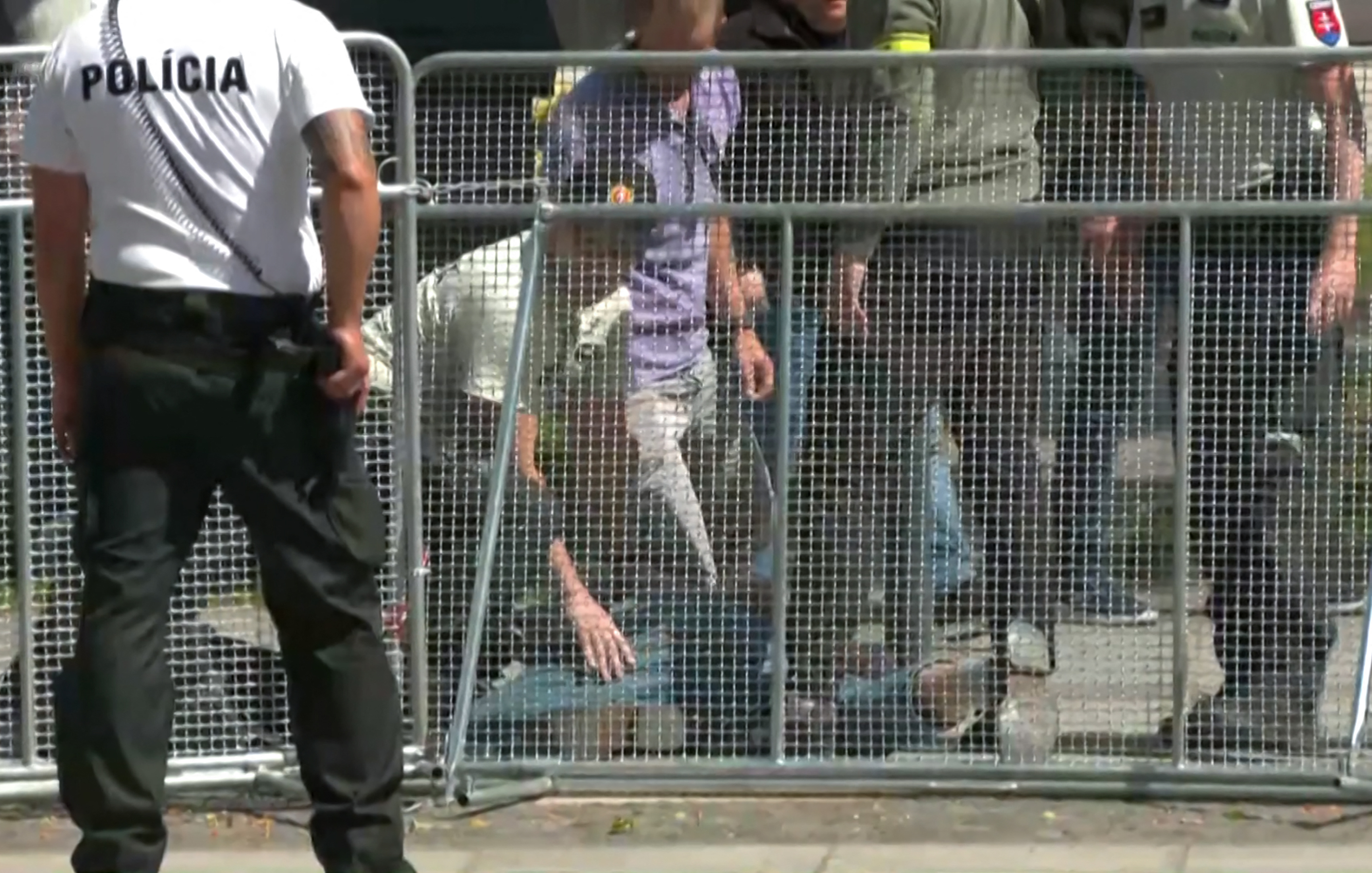 Security personnel apprehending the suspected gunman after the attack on Fico. The man is on the ground behind barrciades. Security men are around him.