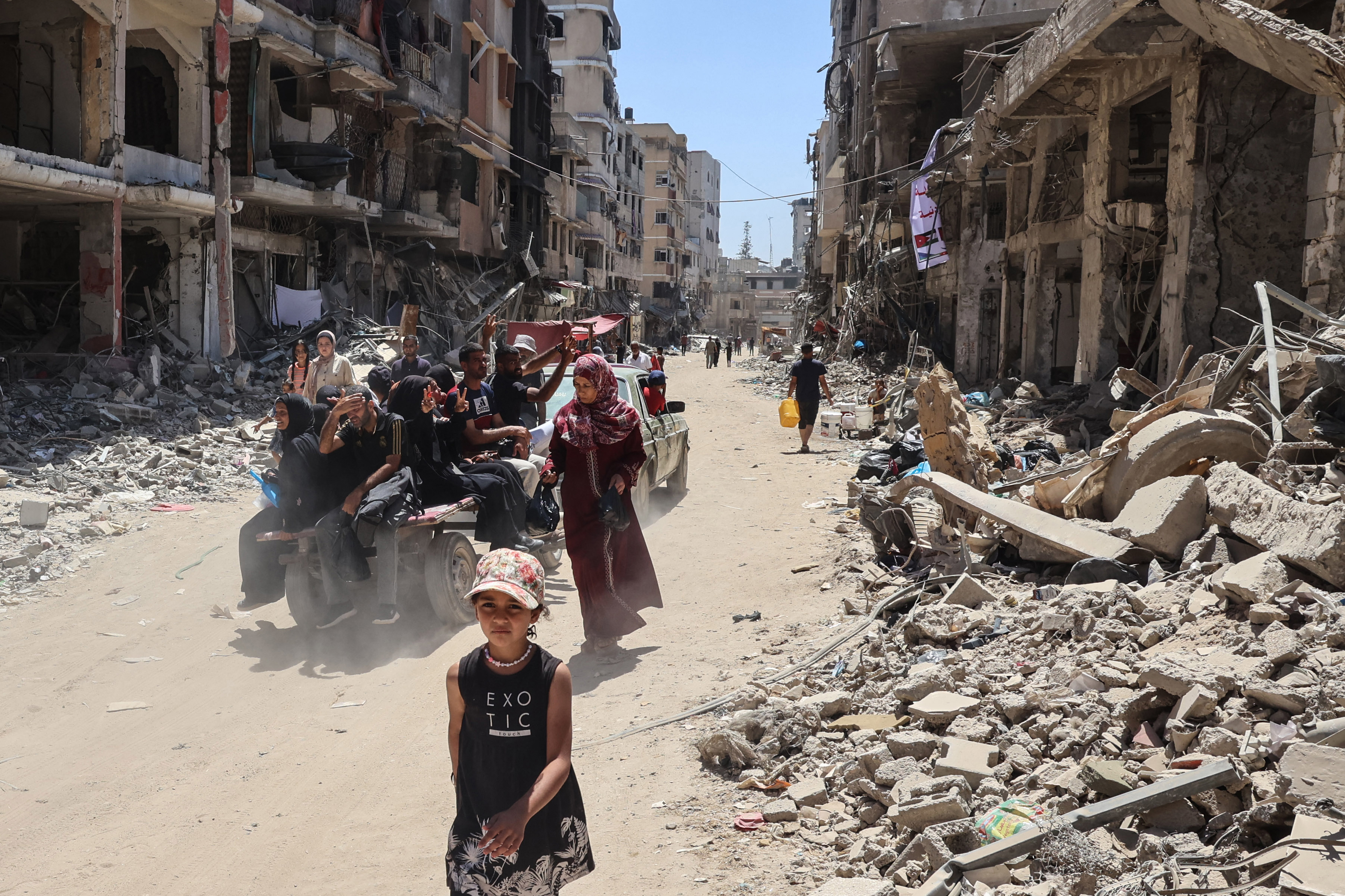 Displaced Palestinians ride in the back of a vehicle along a devastated street in Khan Yunis in the southern Gaza Strip