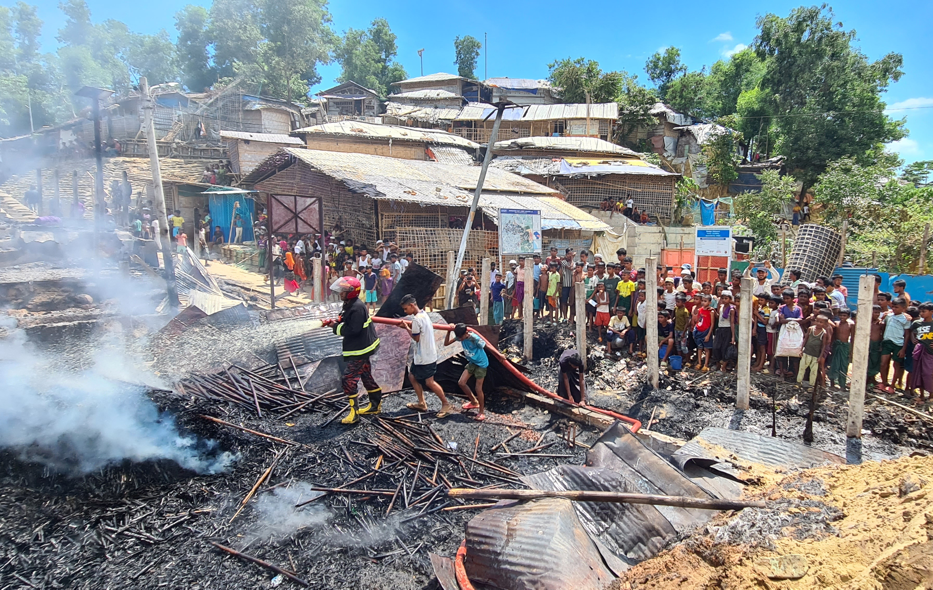 Rohingya refugees look through the debris of their houses charred by a fire at the Ukhia camp in Cox's Bazar on May 24, 2024. (Photo by AFP)