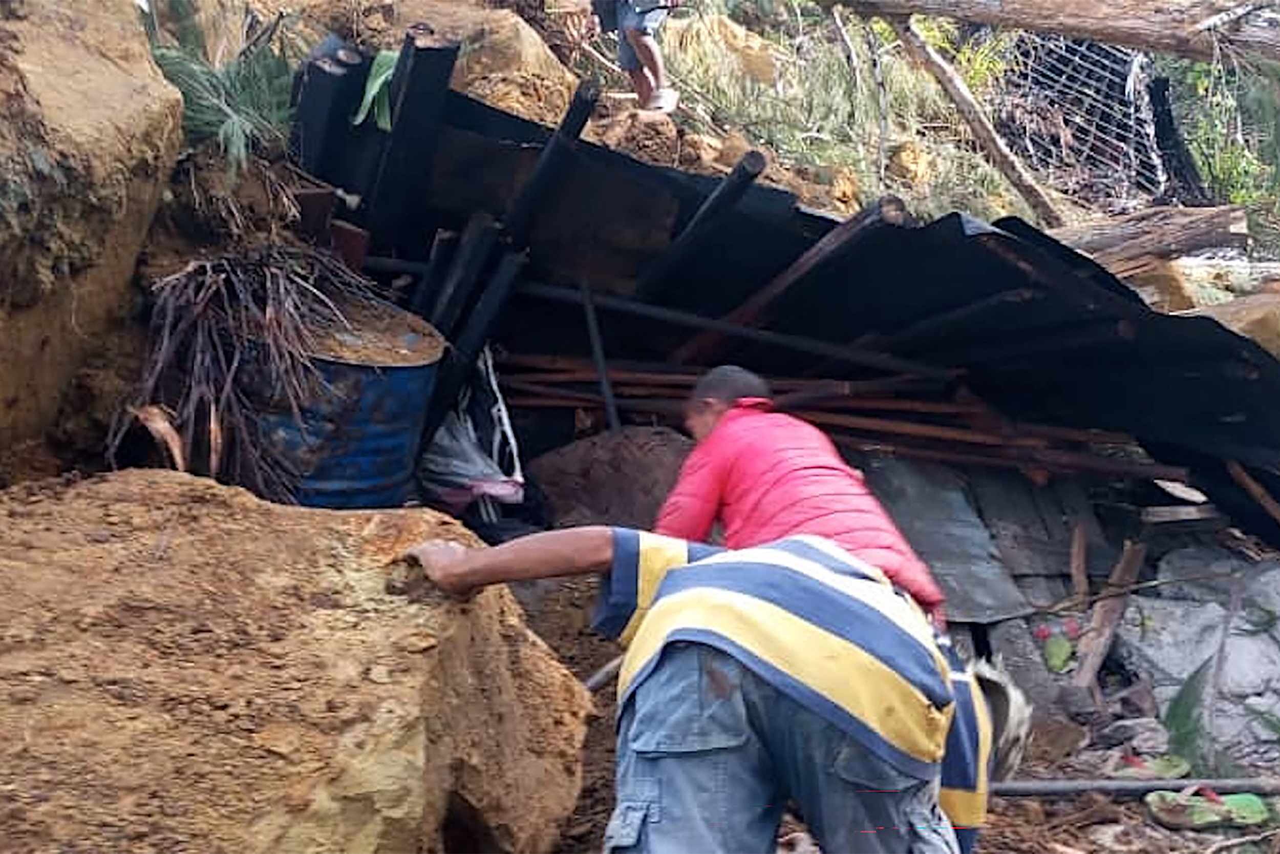 Locals look into a demolished house at the site of a landslide at Yambali Village in the region of Maip Mulitaka, in Papua New Guinea's Enga Province on May 25, 2024. Rescue teams began arriving at the site of a massive landslide in Papua New Guinea's remote highlands on May 25, helping villagers search for the scores of people feared dead under the towering mounds of rubble and mud. (Photo by AFP)