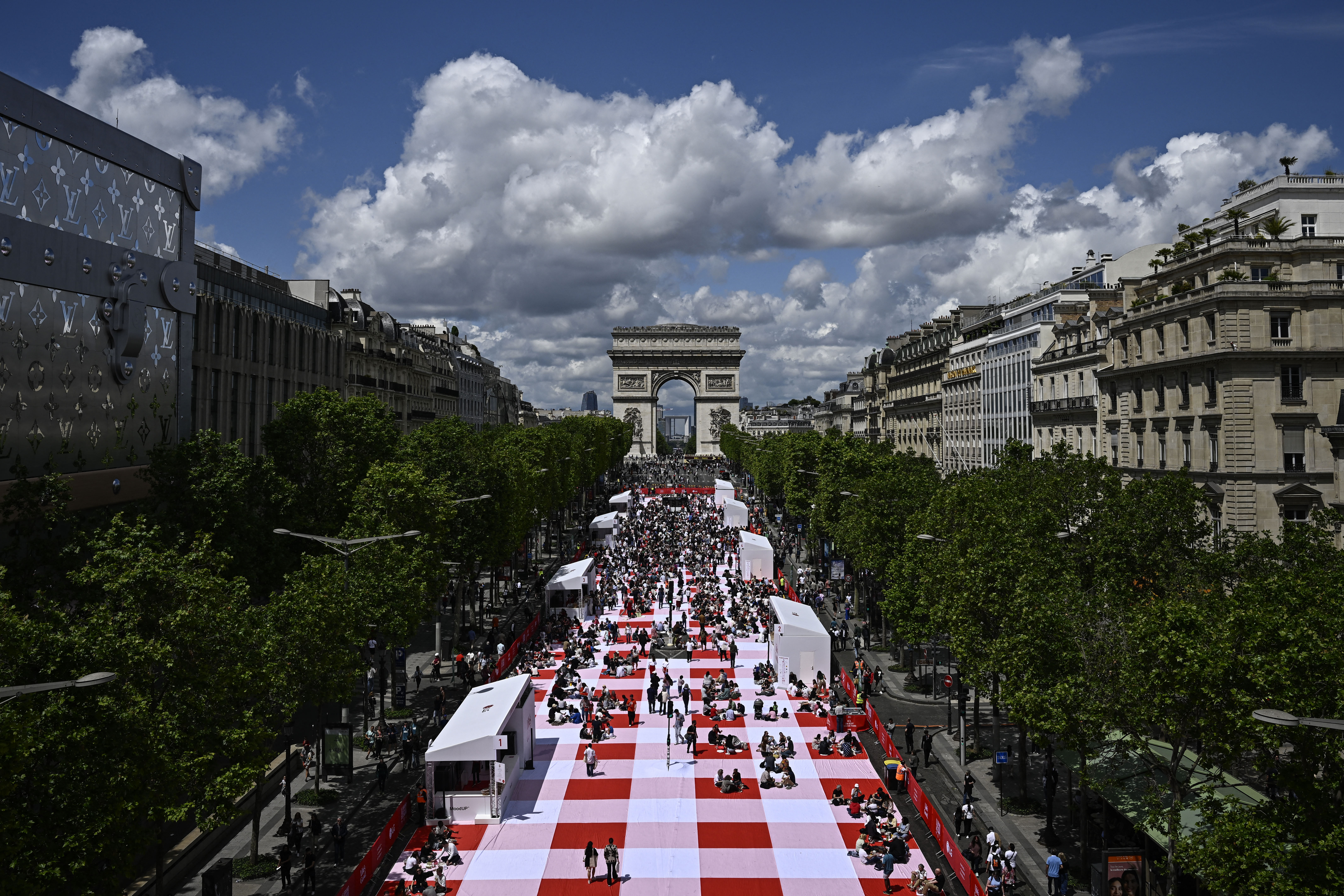 People take part in a giant open-air picnic on the Champs-Elysees avenue in Paris on May 26
