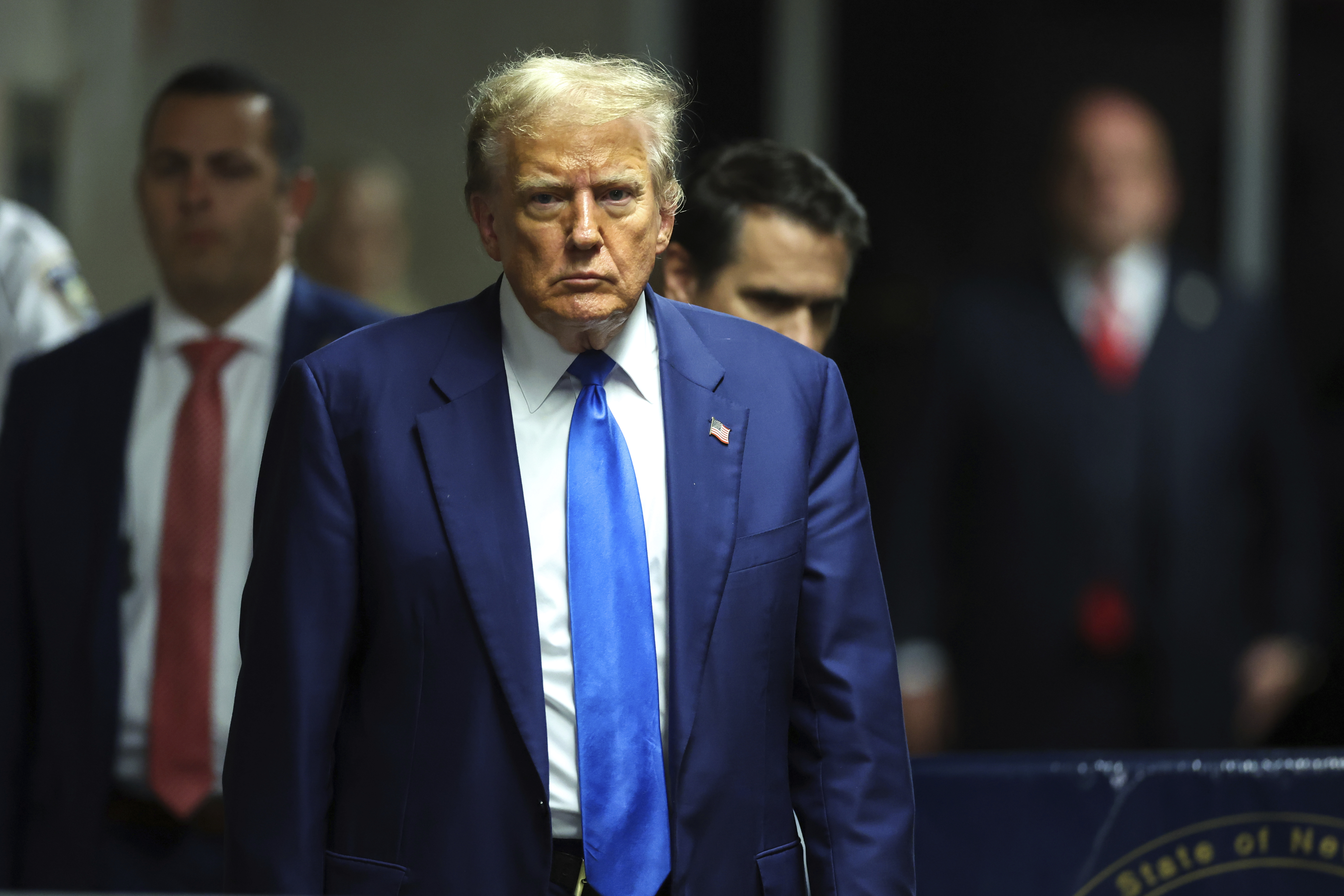 Donald Trump, in a dark blue suit and light blue tie, walks to court.