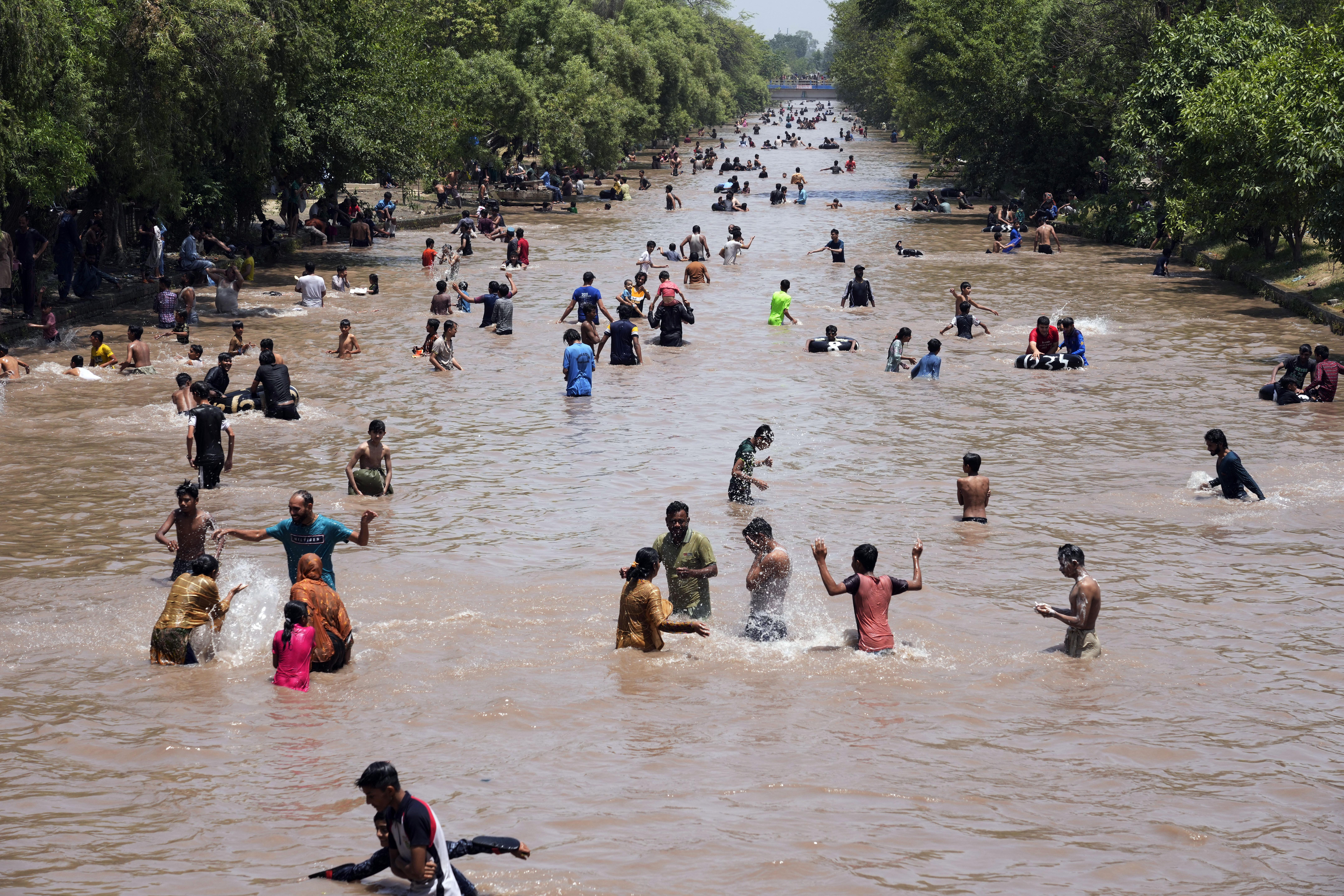 Pakistani youths cool themselves off in a canal during hot weather in Lahore, Pakistan, Sunday, May 26