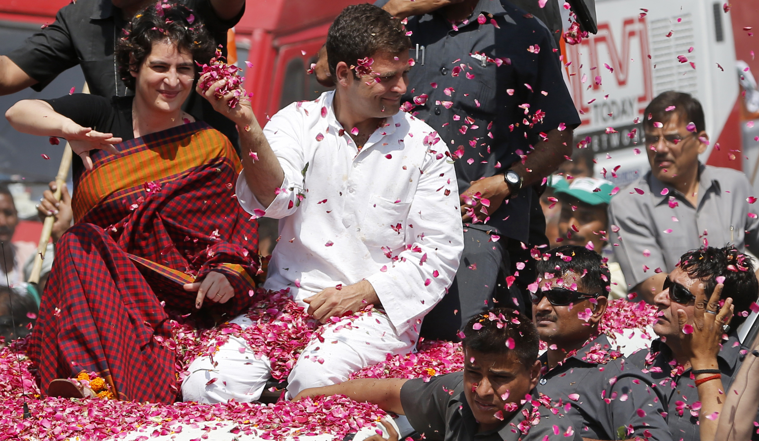 Vice President of Indias ruling Congress party Rahul Gandhi, second right, holds a handful of flower petals to throw back at supporters, with his sister Priyanka Vadra seated by his side as he arrives to file his nomination for the ongoing general elections in Amethi, in the northern Indian state of Uttar Pradesh, Saturday, April 12, 2014. Gandhi, heir to the country's Nehru-Gandhi political dynasty, is leading the struggling party's campaign in the general election. The multiphase voting across the country runs until May 12, with results for the 543-seat lower house of parliament announced May 16. (AP Photo/ Rajesh Kumar Singh)