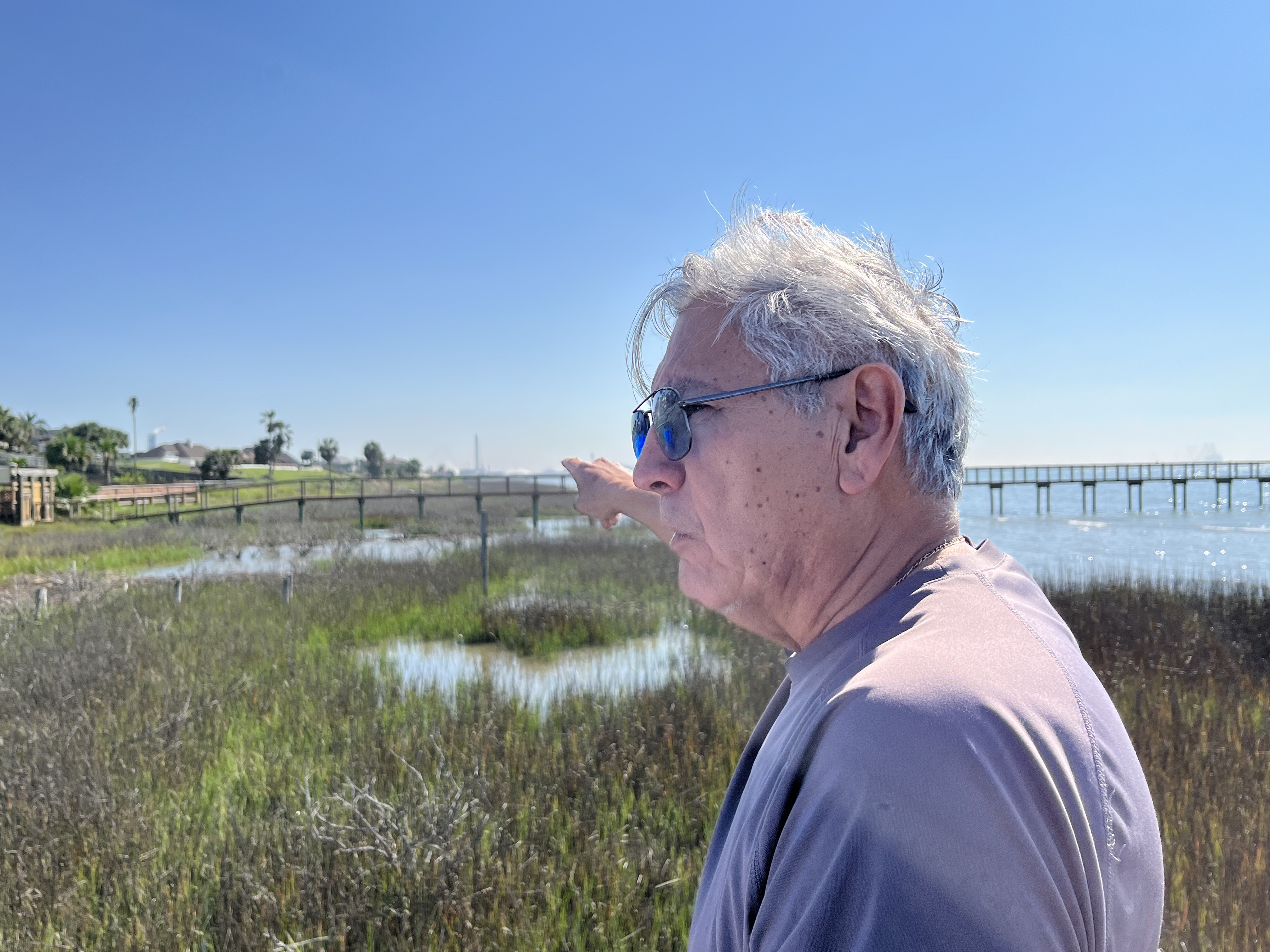 Encarnacion 'Chon' Serna points at the construction of petrochemical plants in Ingleside, seen from his home in Portland, Corpus Christi, Texas, the United States [Aina Marzia/Al Jazeera]
