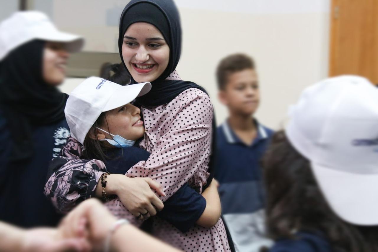 Hala Sharaf wears a black hijab and hugs her friend in the Gaza Strip. [Al Jazeera/Hala Sharaf]