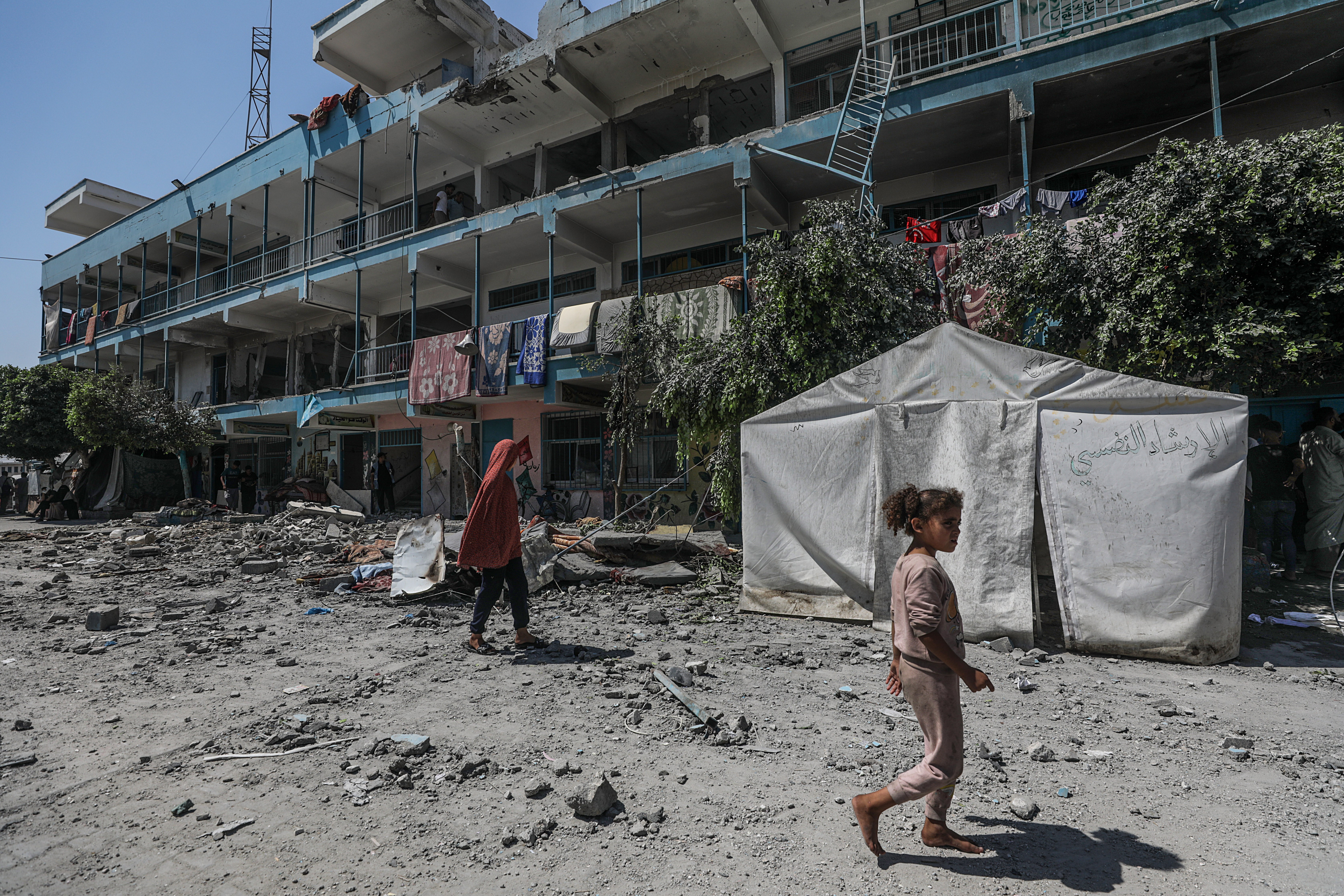 epa11392940 Internally displaced Palestinians walk in the courtyard of a destroyed UNRWA school following an Israeli air strike in Al Nusairat refugee camp in the central Gaza Strip on, 06 June 2024. According to the Palestinian News Agency Wafa, at least 32 people were killed and dozens others were injured on early 06 June following an Israeli strike on a UNRWA school sheltering displaced Palestinians, located in the Nuseirat refugee camp in the central Gaza strip. The Israeli army said that it had "conducted a precise strike on a Hamas compound", whose members were " embedded in the UNRWA school". More than 36,000 Palestinians and over 1,400 Israelis have been killed, according to the Palestinian Health Ministry and the Israel Defense Forces (IDF), since Hamas militants launched an attack against Israel from the Gaza Strip on 07 October 2023, and the Israeli operations in Gaza and the West Bank which followed it. EPA-EFE/MOHAMMED SABER