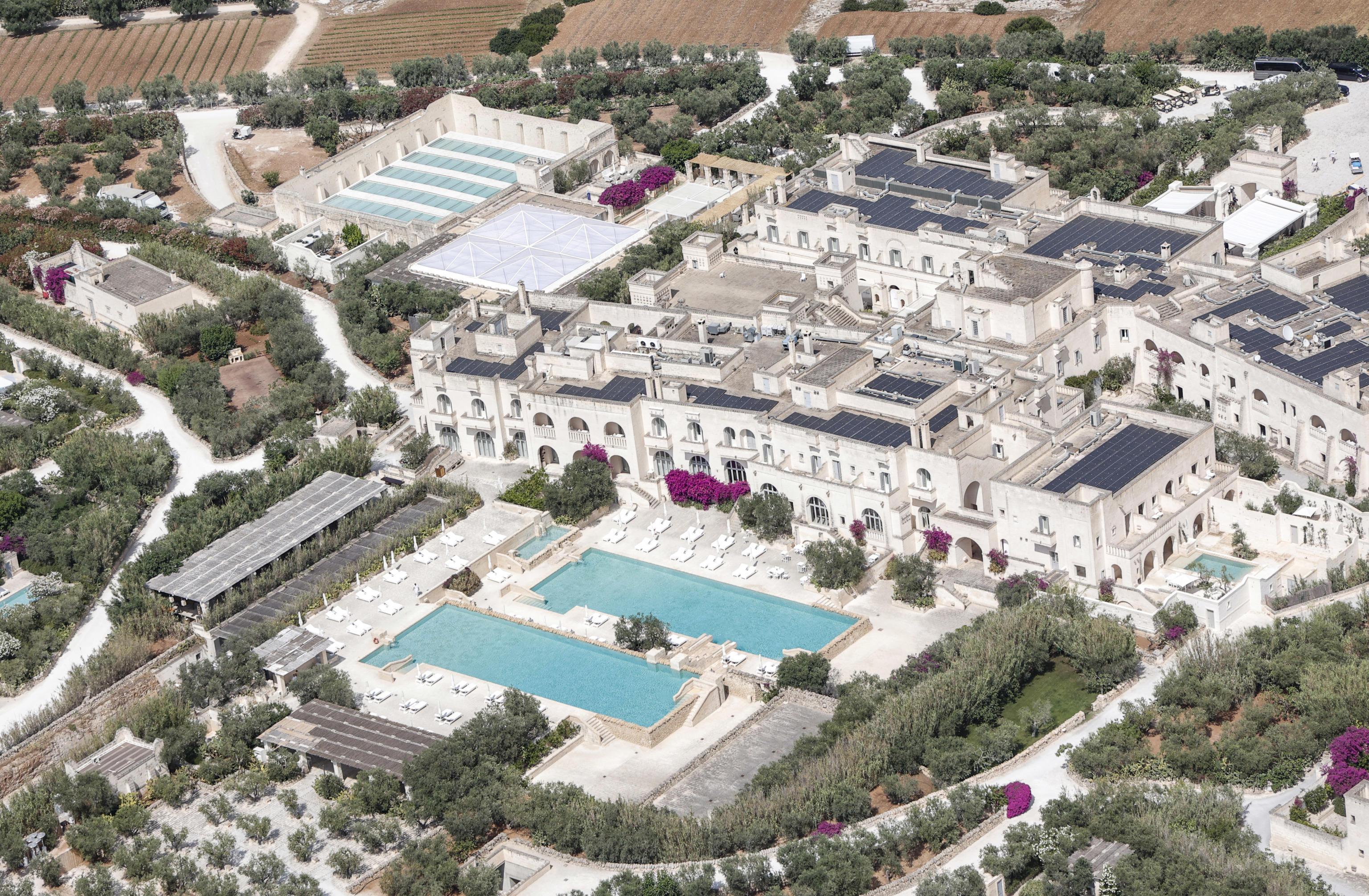 An aerial. view of the Borgo Egnazia resort. It's in the syle of a medieval village and has two swimming pools side by side