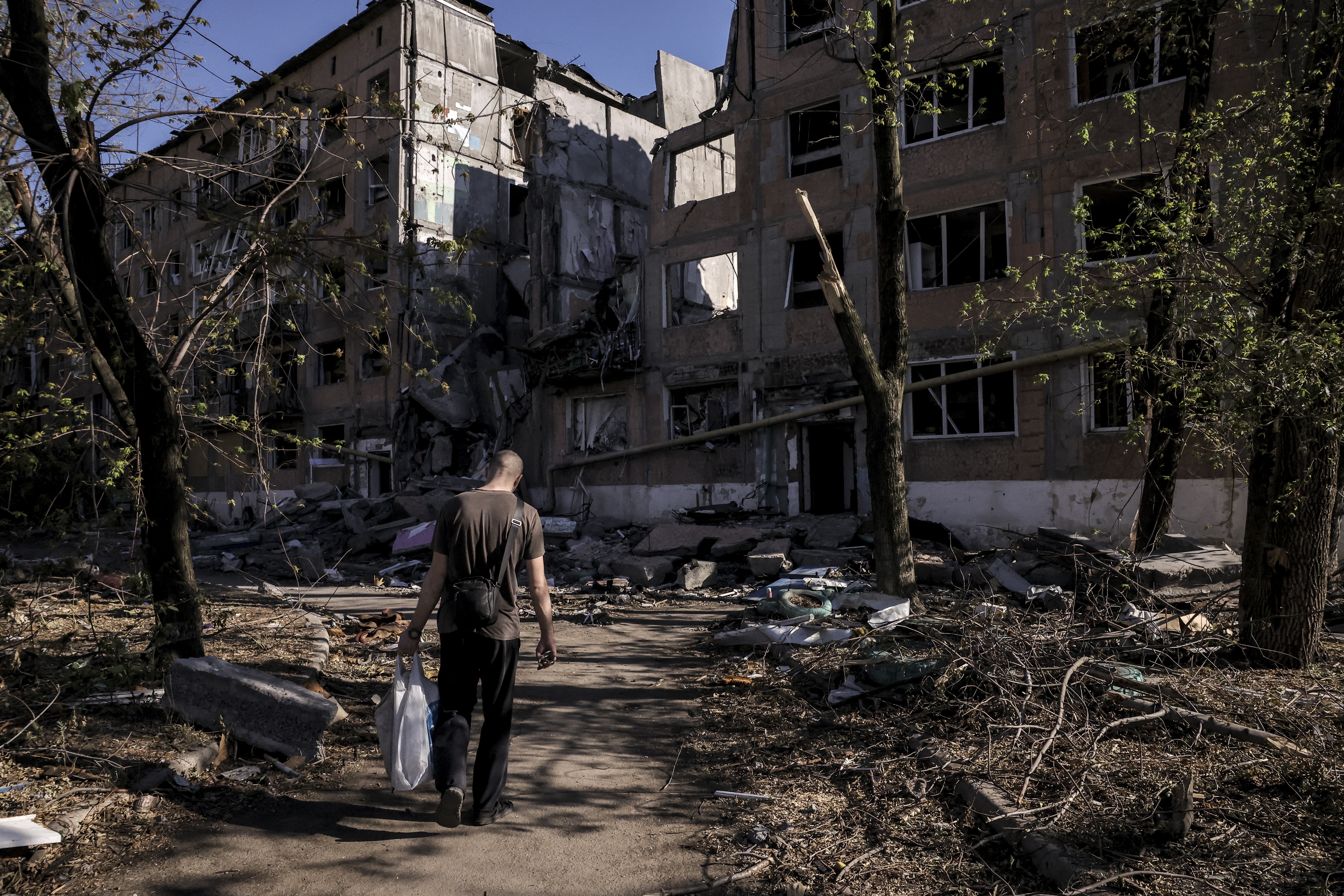 A man walking past a destroyed block of flats in Toretsk near the front line