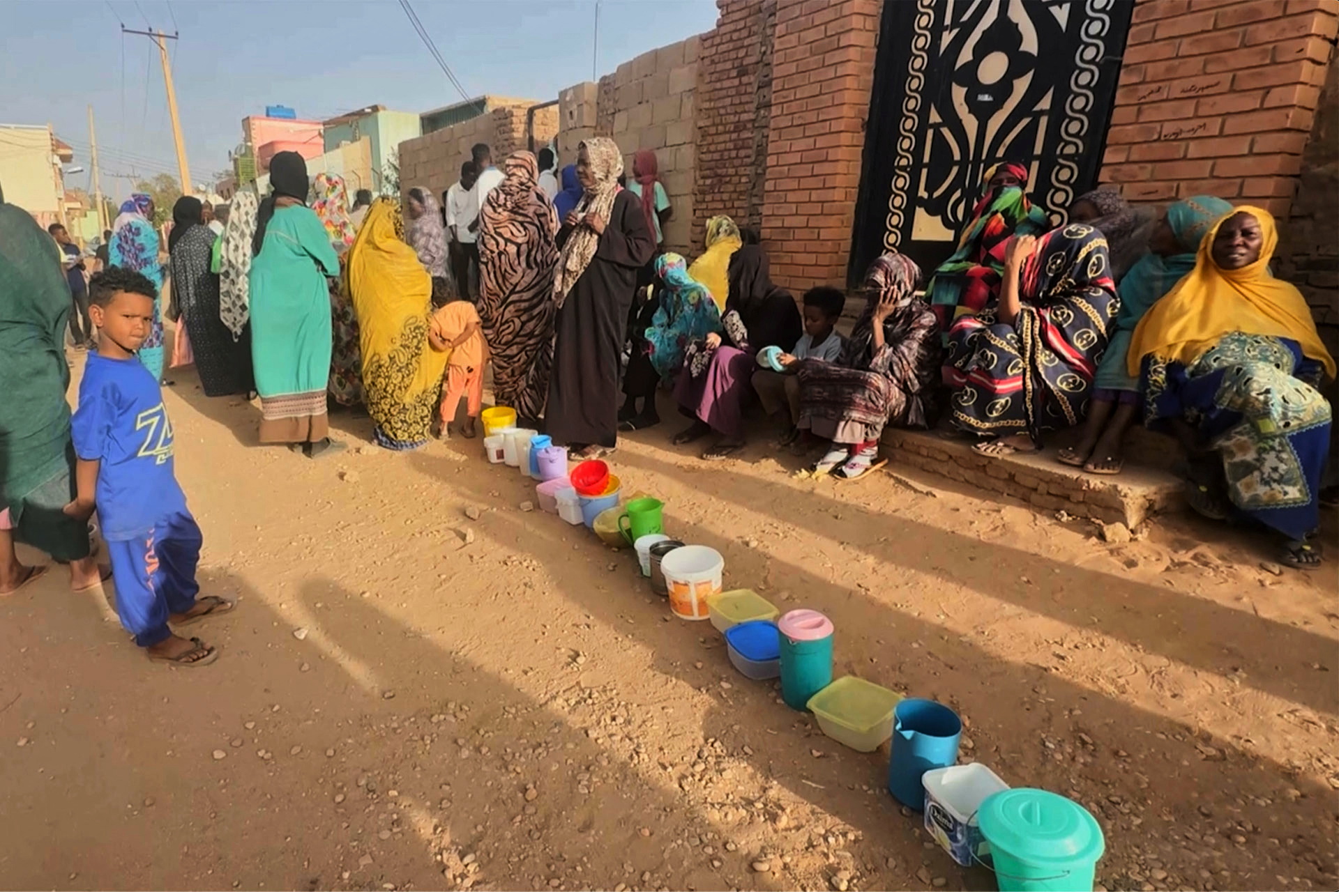 Residents wait to collect food in containers from a soup kitchen in Omdurman, Sudan, on March 11, 2024 [El Tayeb Siddig/Reuters]