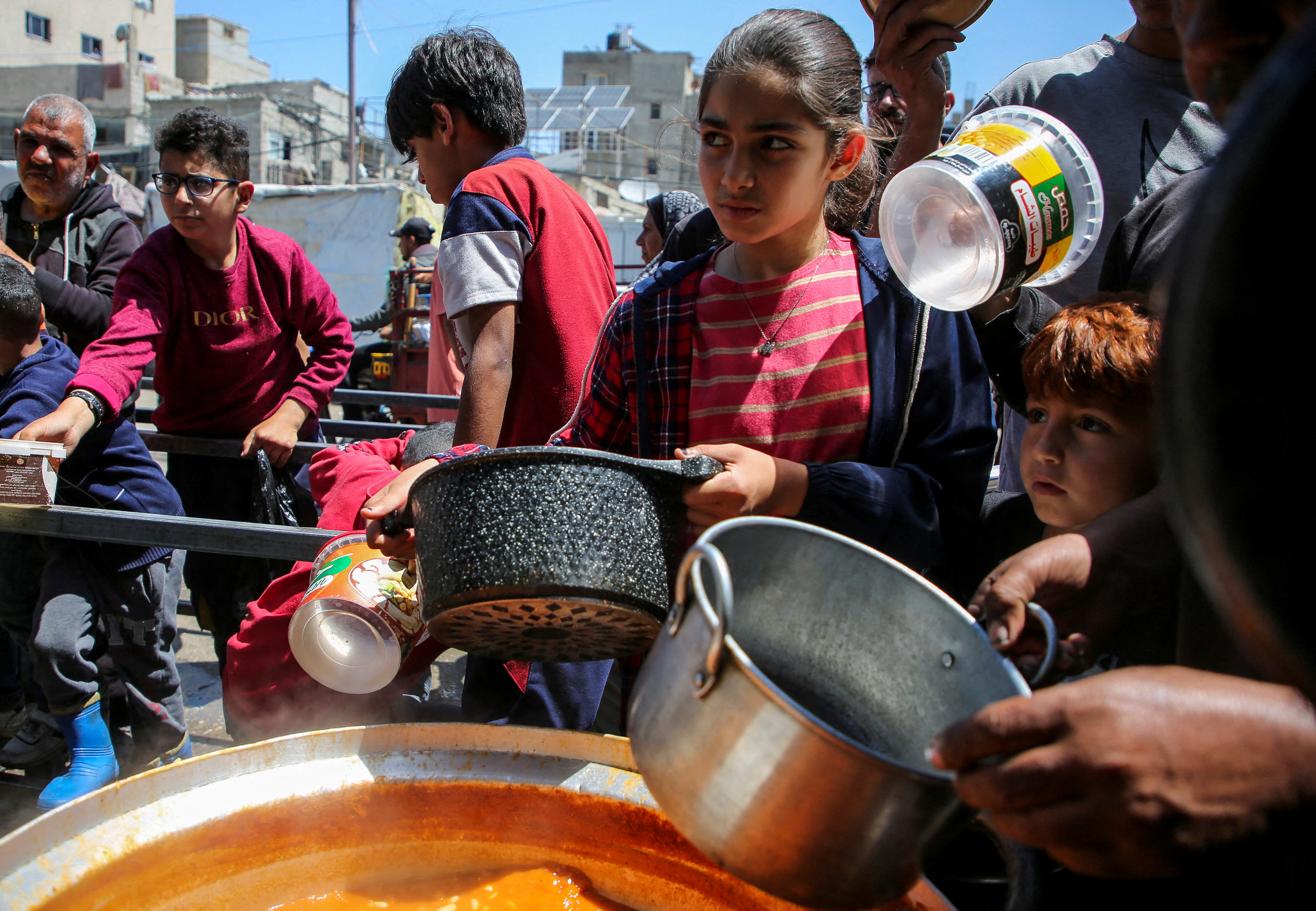 Children hold pots to receive food