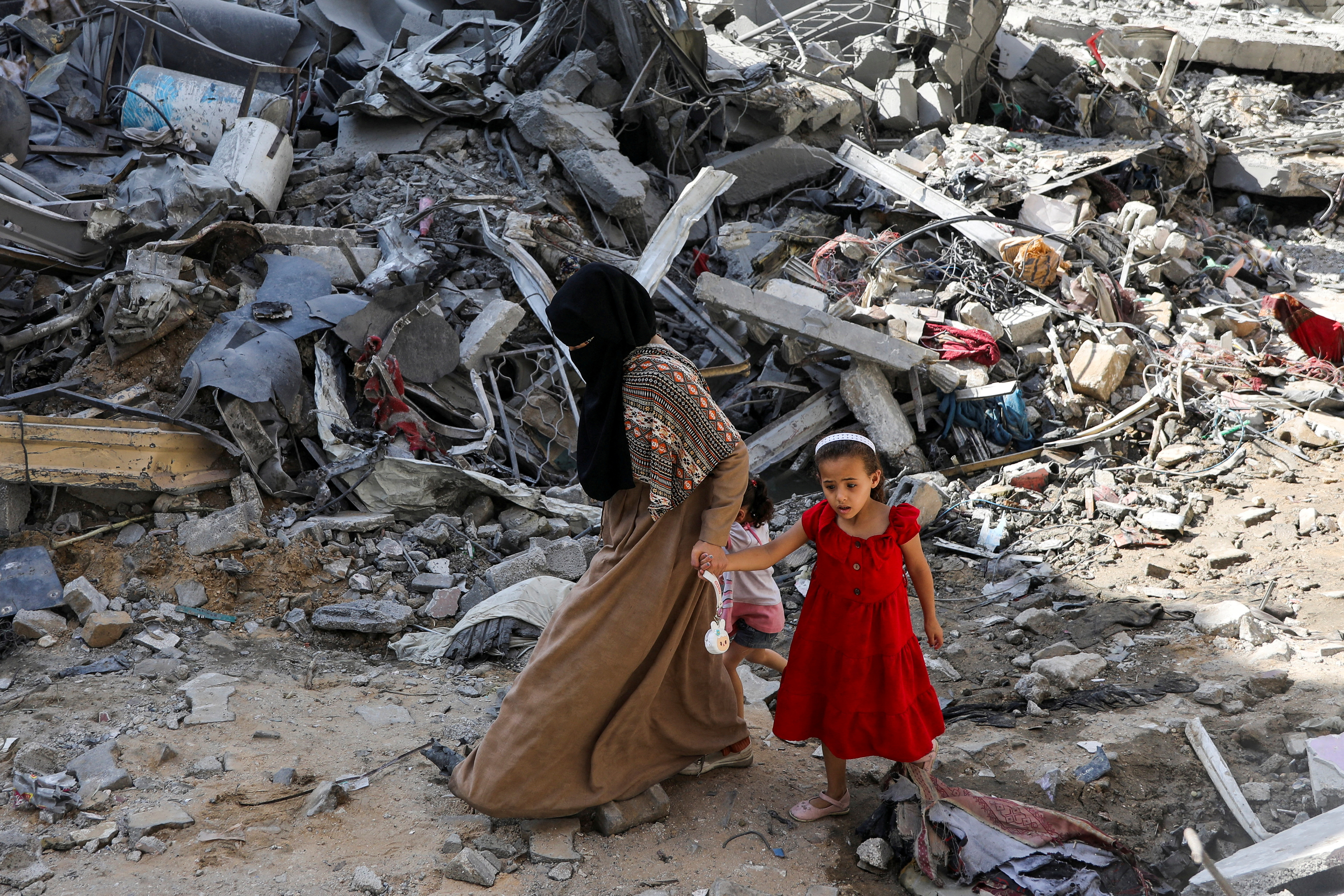 A woman and child walk among debris, aftermath of Israeli strikes at the area, where Israeli hostages were rescued on Saturday, as Palestinian death toll rises to 274, amid the Israel-Hamas conflict, in Nuseirat refugee camp in the central Gaza Strip, June 9, 2024. REUTERS/Abed Khaled TPX IMAGES OF THE DAY