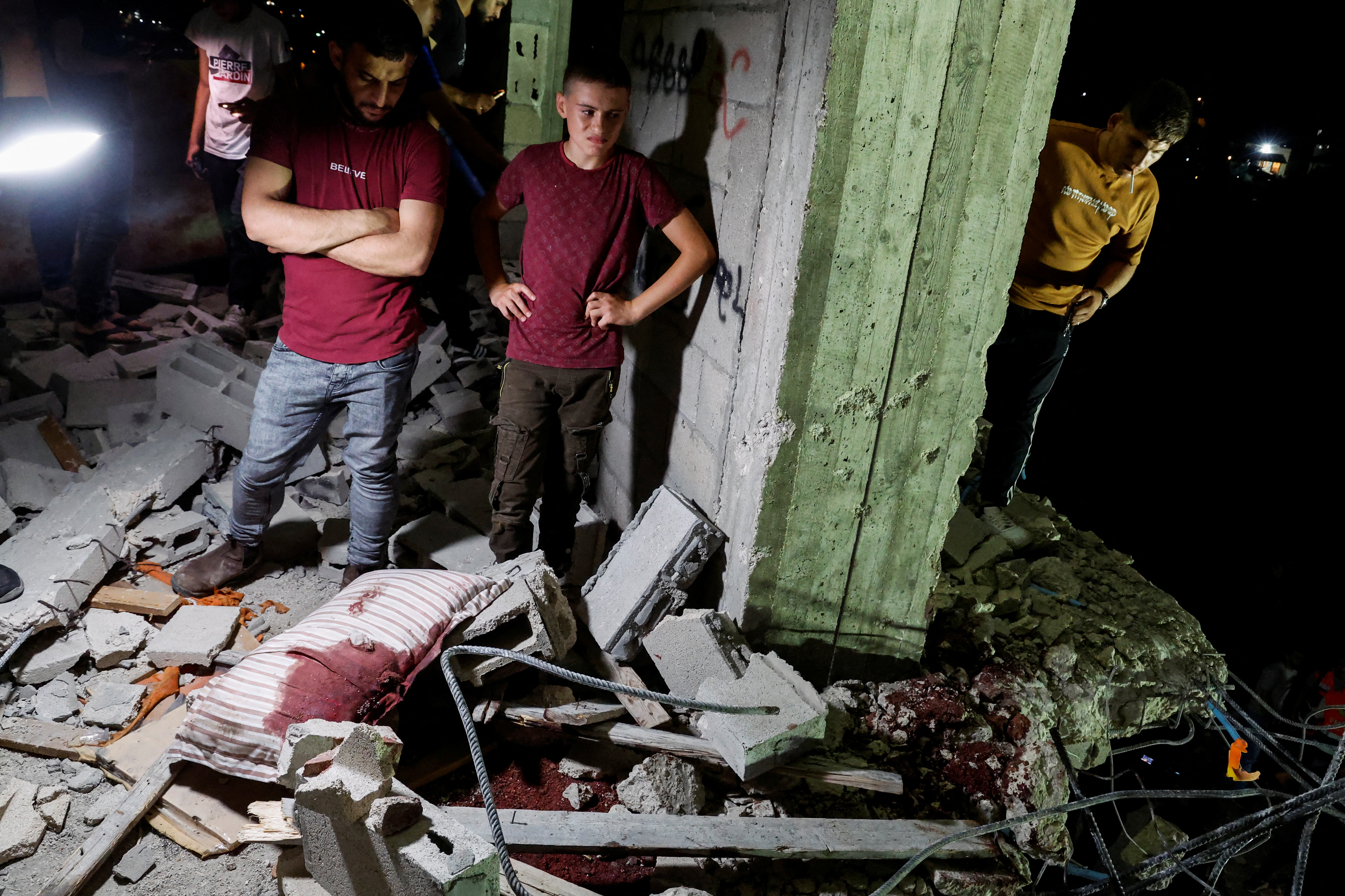 SENSITIVE MATERIAL. THIS IMAGE MAY OFFEND OR DISTURB Palestinians stand near blood stains as they inspect a damaged building following an Israeli military operation, in Qabatiya, near Jenin, in the Israeli-occupied West Bank, June 13, 2024. REUTERS/Raneen Sawafta