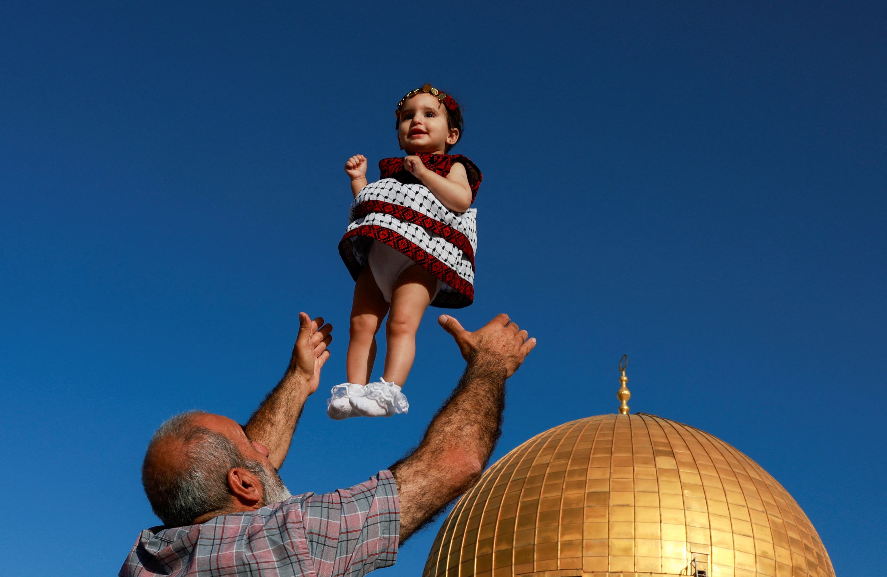 A man throws a girl in the air as Palestinians gather on the first day of the Muslim holiday of Eid al-Adha at the Al-Aqsa compound, also known to Jews as the Temple Mount, in Jerusalem's Old City June 16