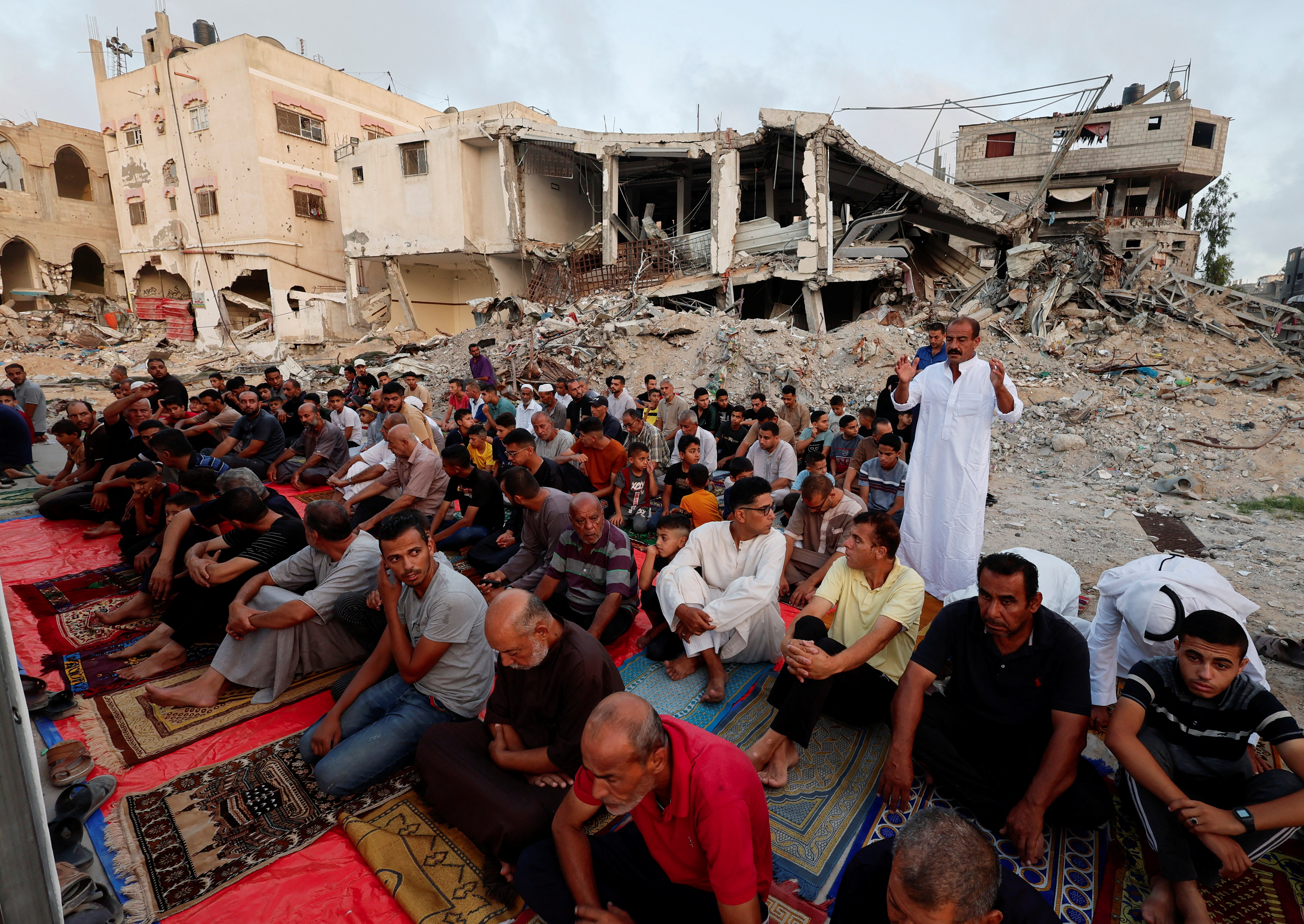 people pray next to a destroyed building