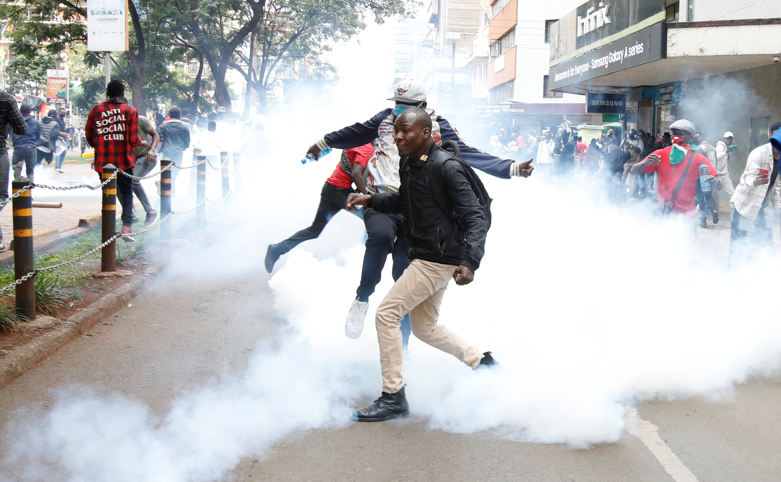 Protestors react after police used teargas to disperse them during a demonstration against Kenya's proposed finance bill