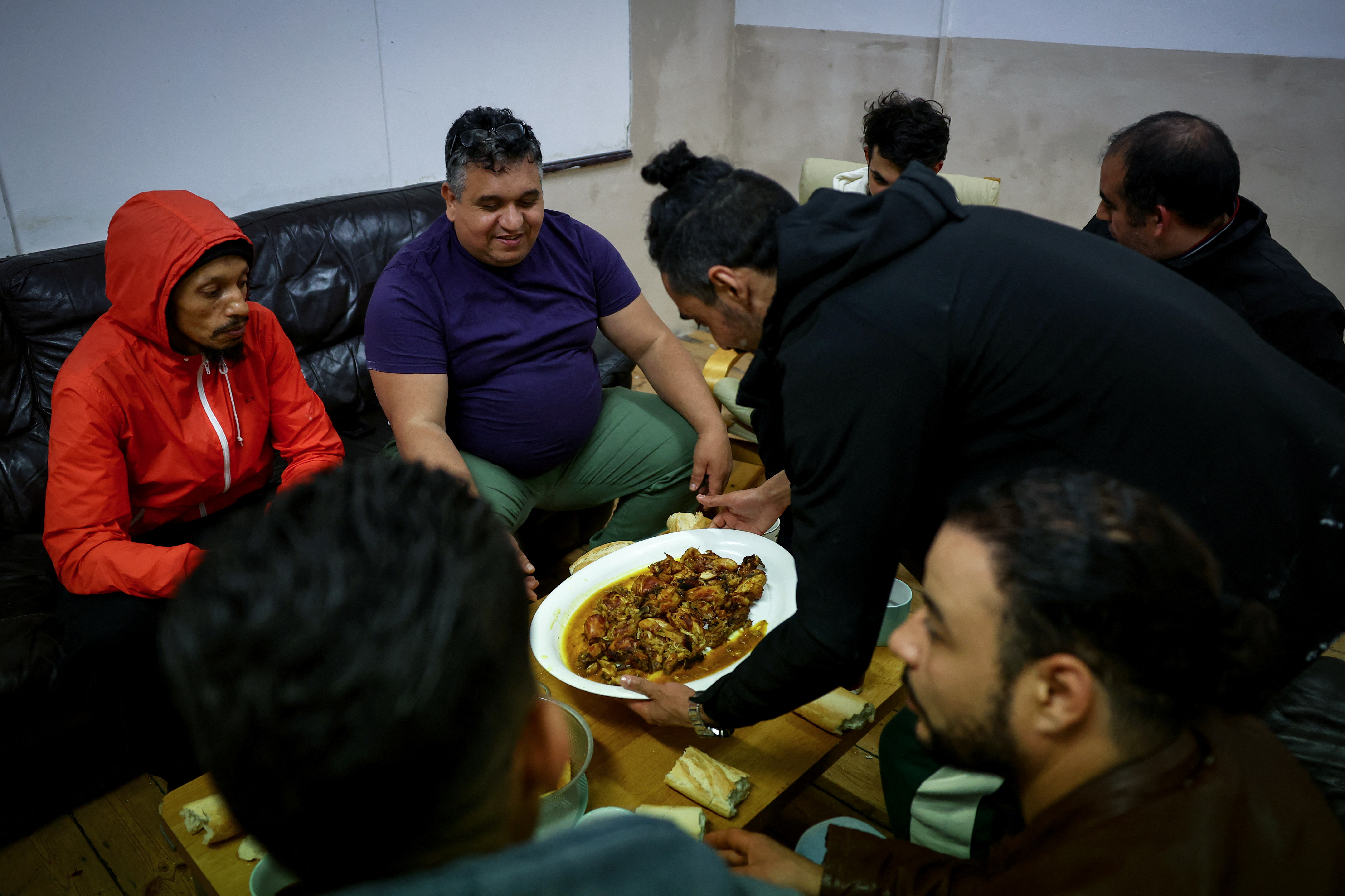 Squatters, including Youness Elaissaoui, 49, (3rd-L) eat an evening meal together in a room used as a common room of the place they live, which was once a school and is now occupied by squatter activist group Reclaim Croydon, in Croydon, south London, Britain, May 16