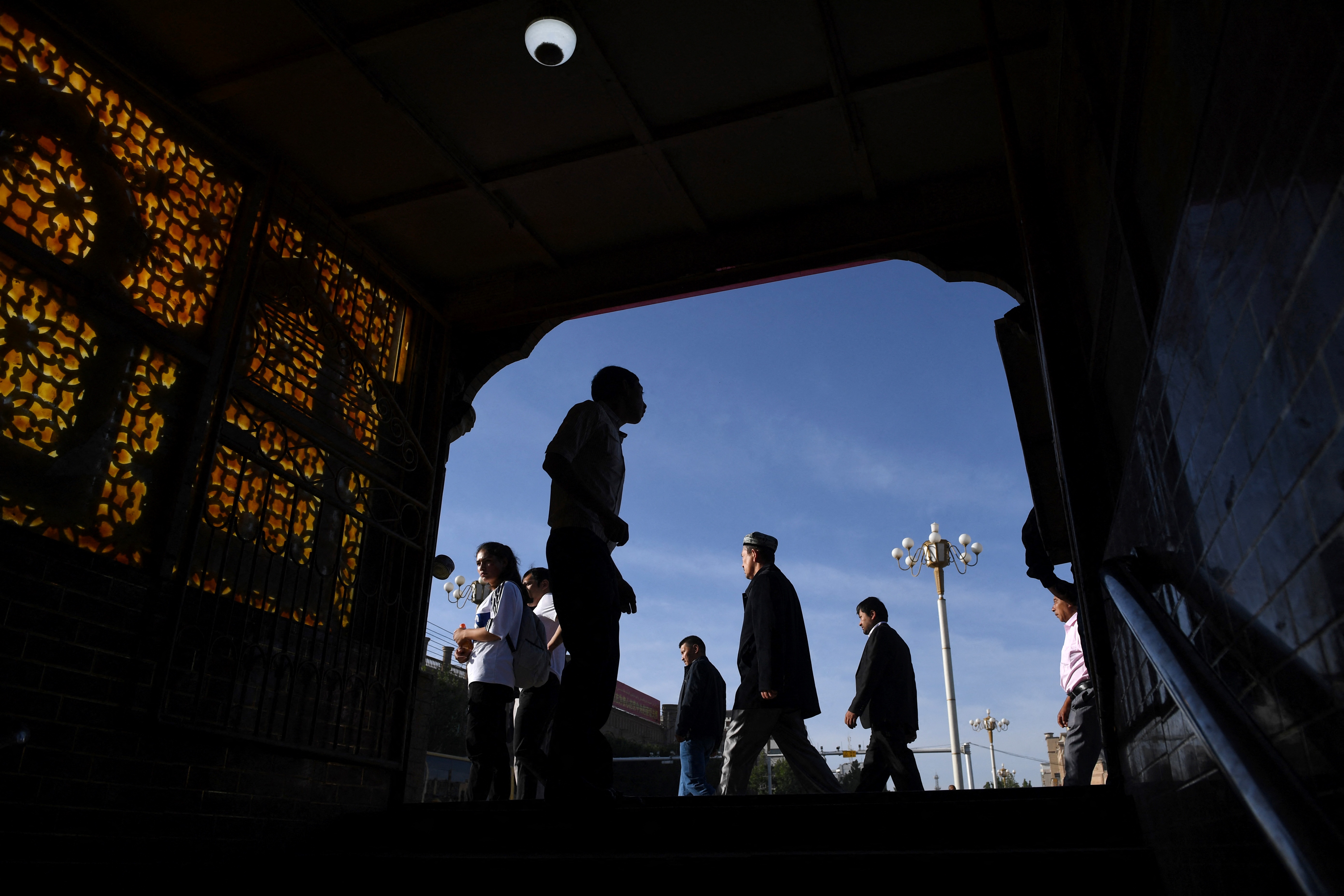 Uighur men silhouetted against the sky after leaving Eid prayers in Kashgar