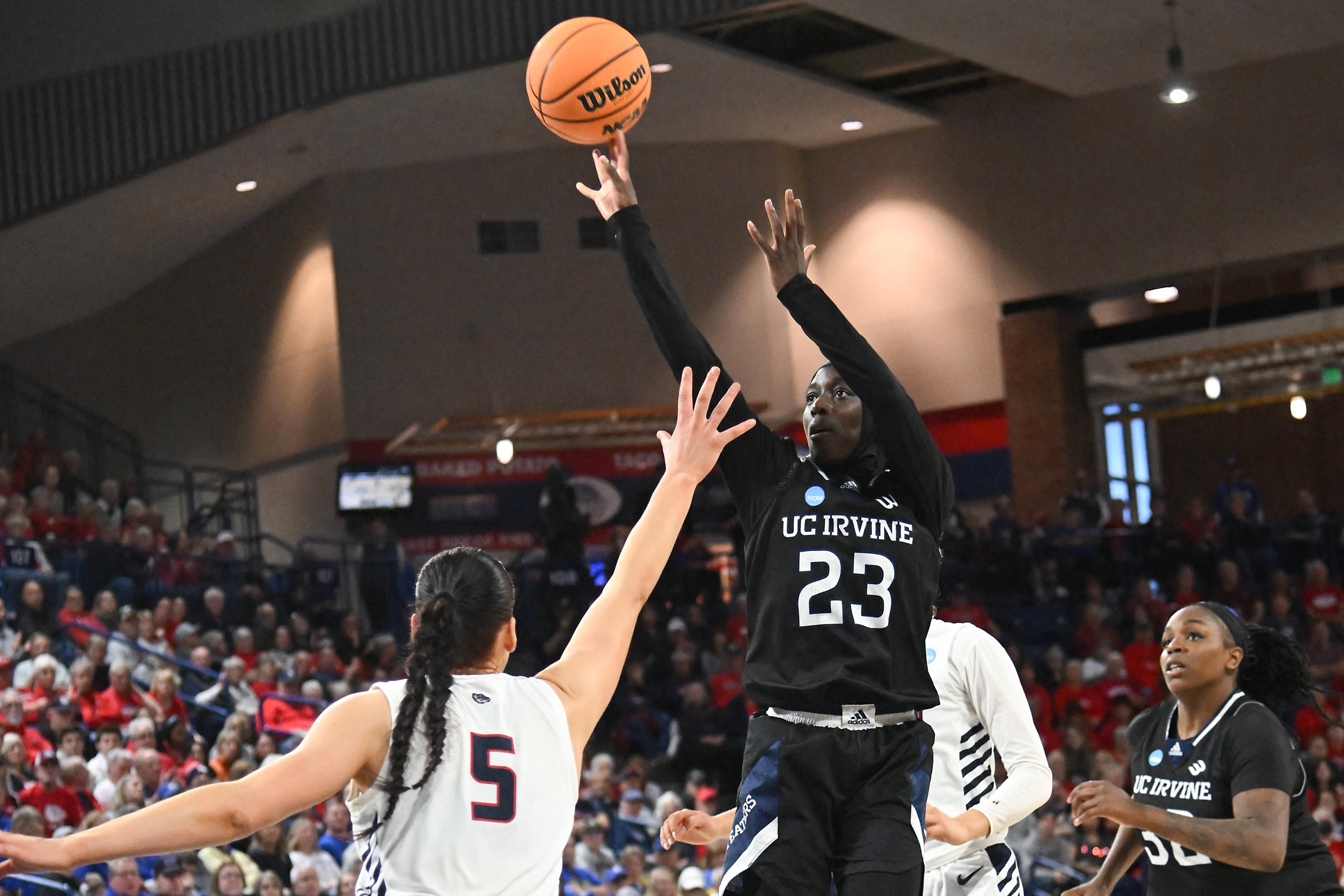 Basketball player shoots over opponent.
