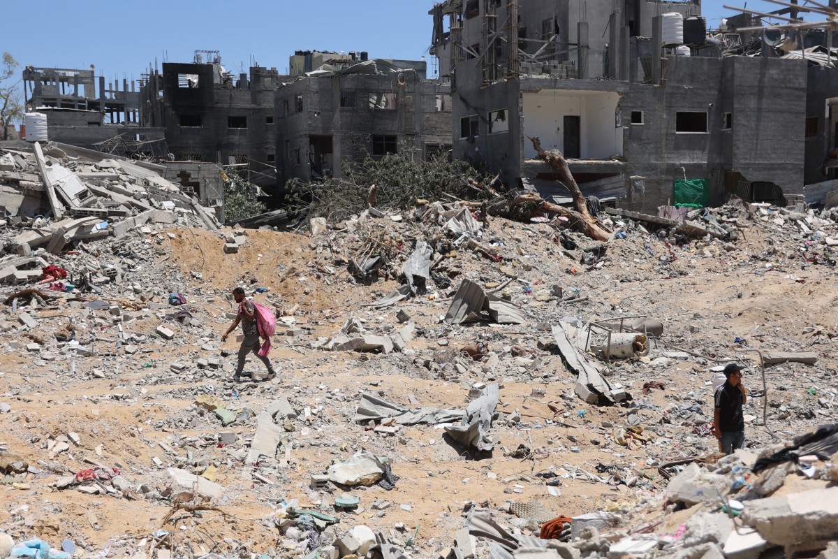 Palestinians walks next to destroyed buildings in the Jabalia