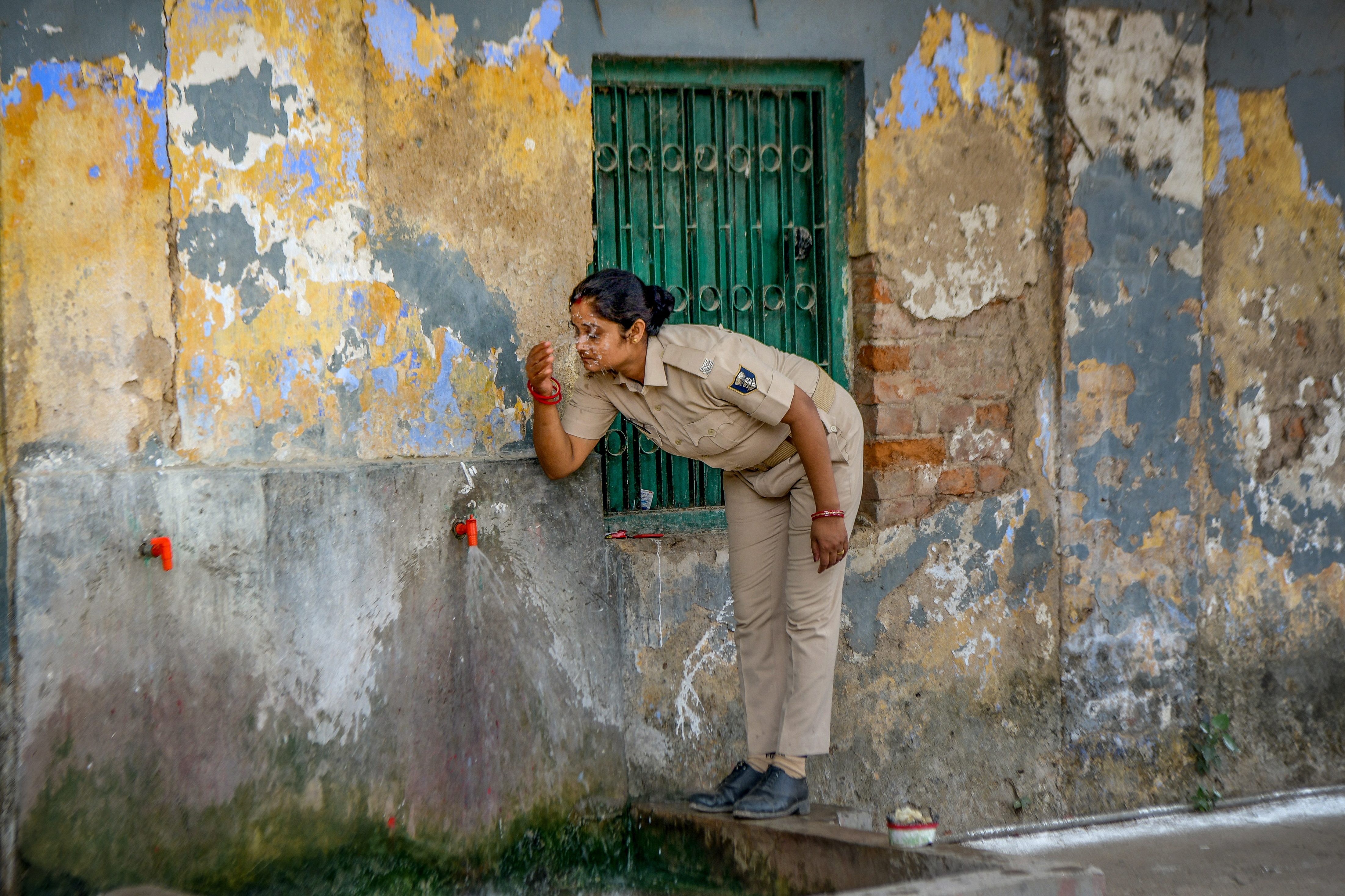 Police personnel deputed on election duty sprinkles tap water on her face on a hot summer day in Patna on June 1