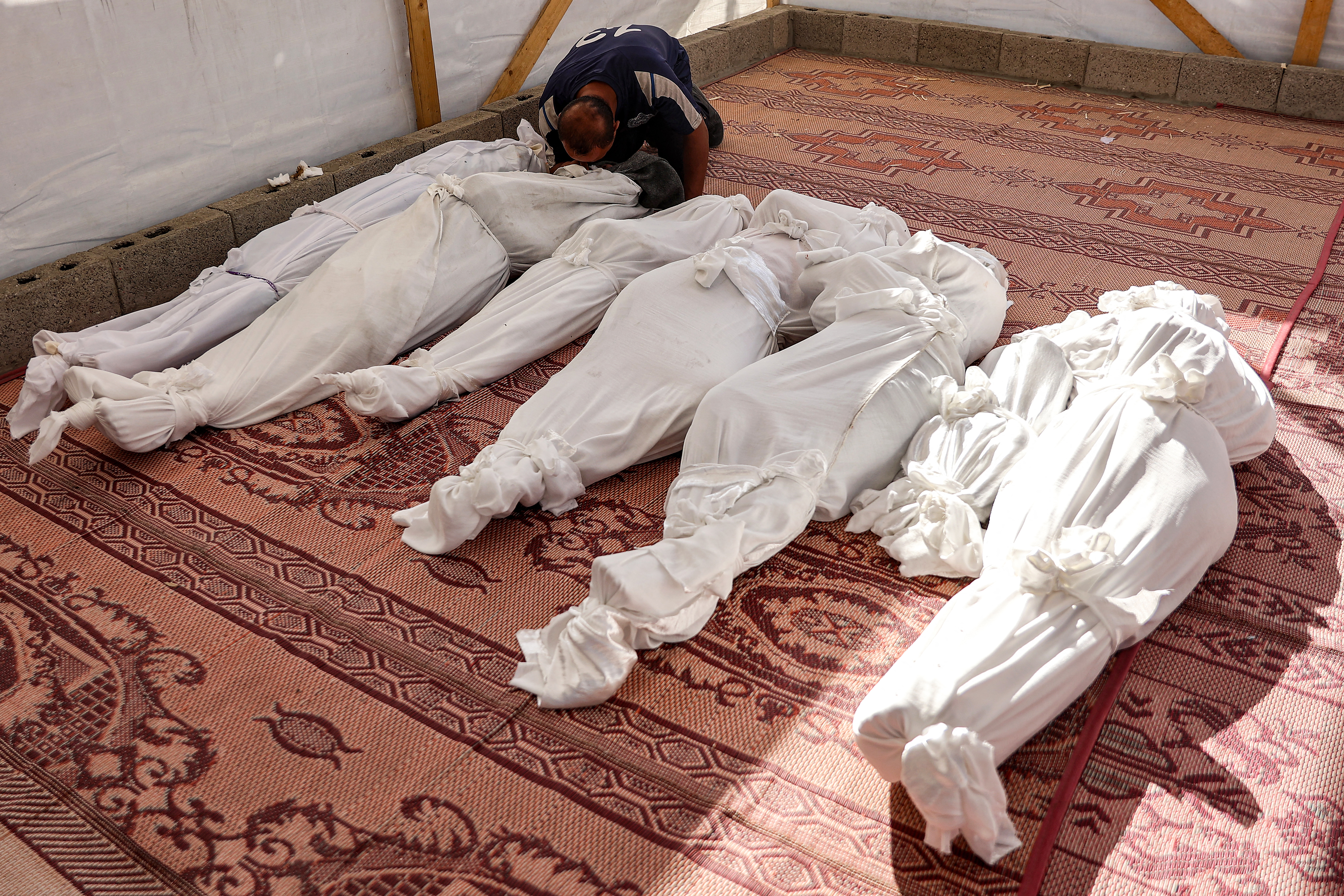 A man mourns by one of the retrieved bodies of victims killed in the aftermath of overnight Israeli bombardment at the Asma school run by the UN Relief and Works Agency for Palestine Refugees