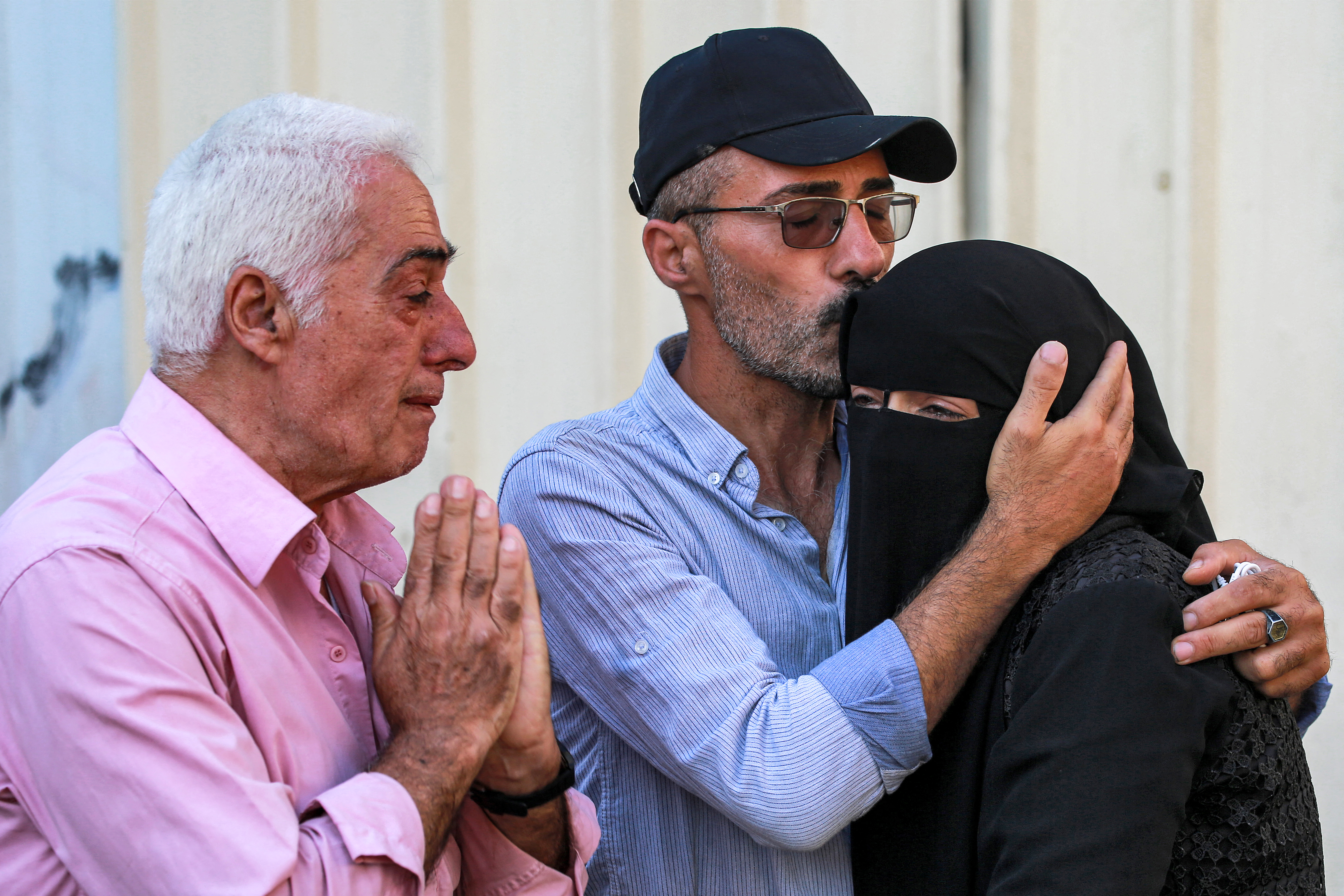 A man comforts a woman reacting as she mourns with others gathering to inspect the bodies of their family members who were killed in the aftermath of overnight Israeli bombardment in al-Maghazi in the central Gaza Strip